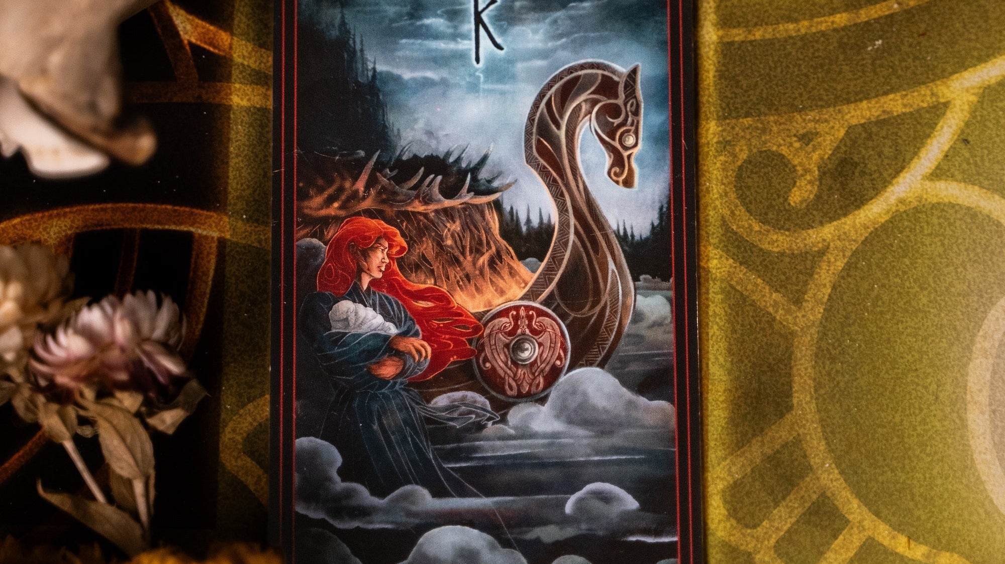 Illustrated tarot-style card featuring a red-haired woman standing beside a Viking longship