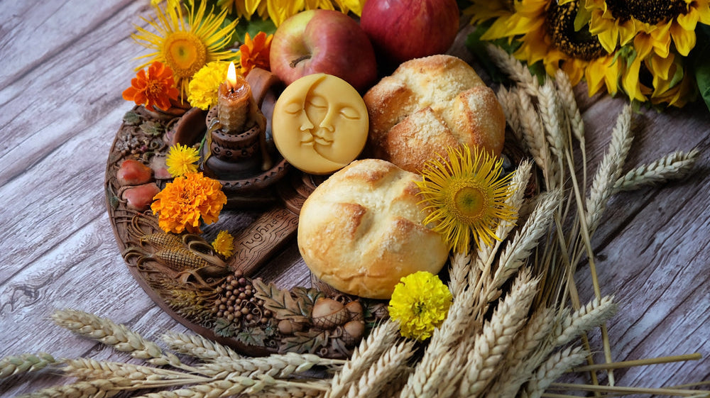 Lughnasadh offering table with fresh bread, sunflowers, apples, marigolds, and candles arranged with wheat stalks