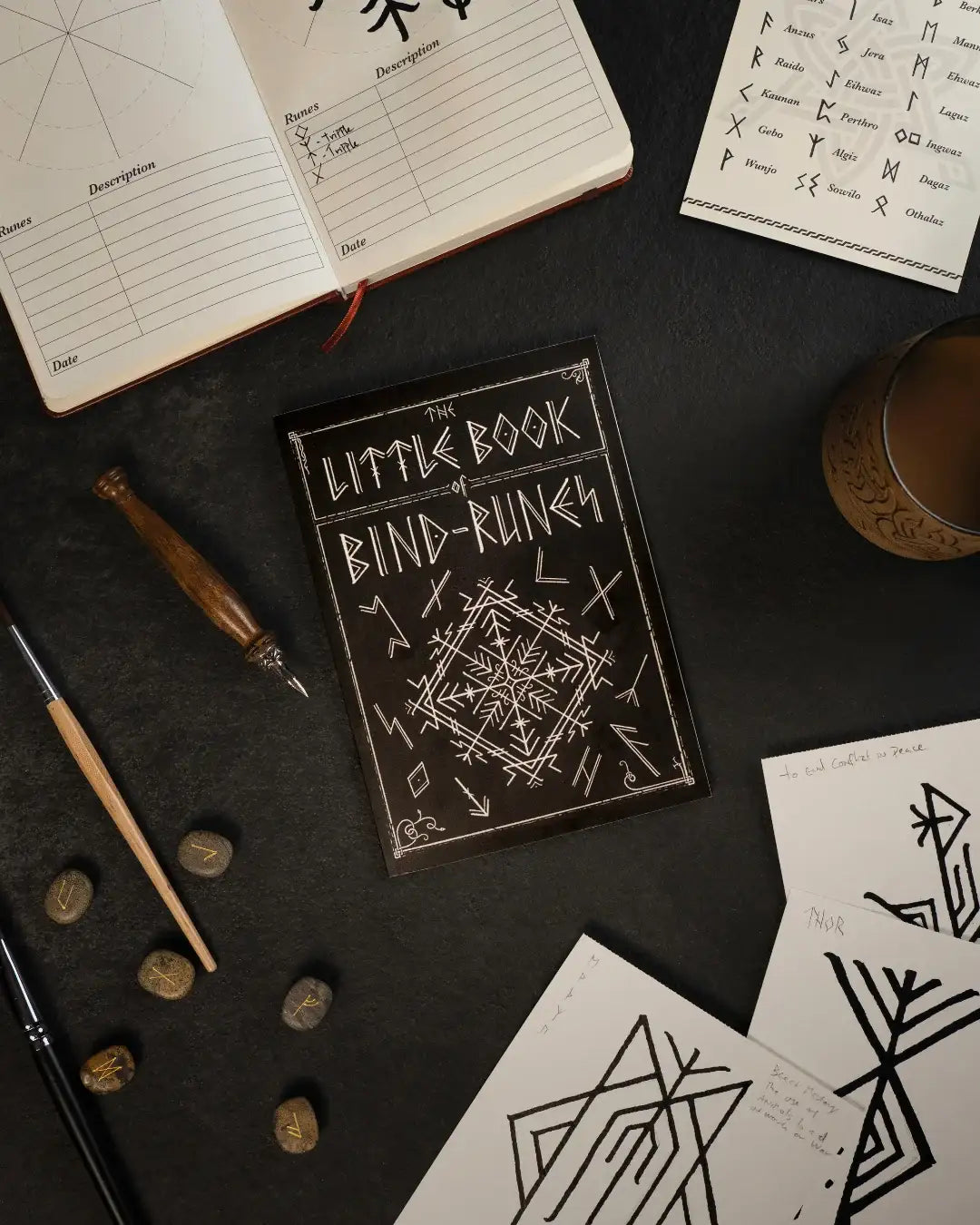 Little Book of Bind-Runes with Norse rune stones, sketchbook, and Viking-inspired tattoo designs on dark surface