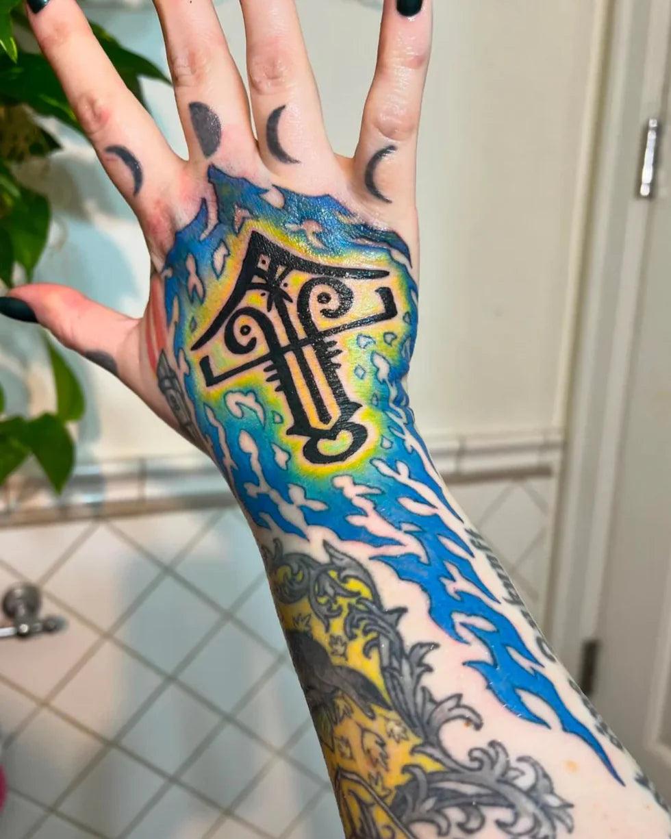 Viking-inspired hand tattoo with Norse runes, blue flames, and crescent moons on fingers
