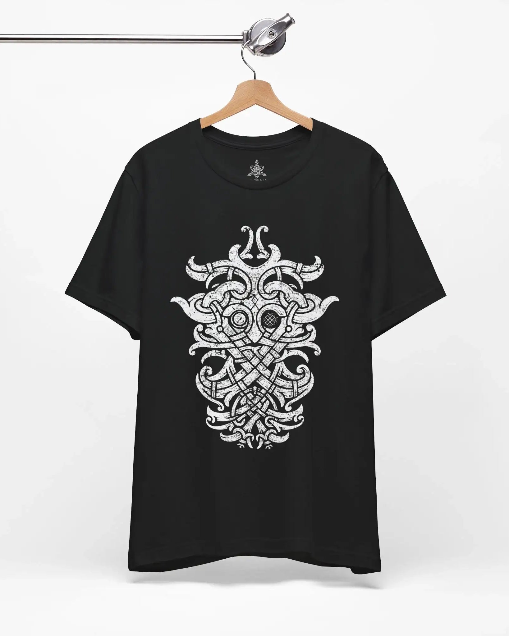 A black short-sleeve t-shirt hanging on a wooden hanger from a metal rack, featuring a large white Norse knotwork design printed on the front.