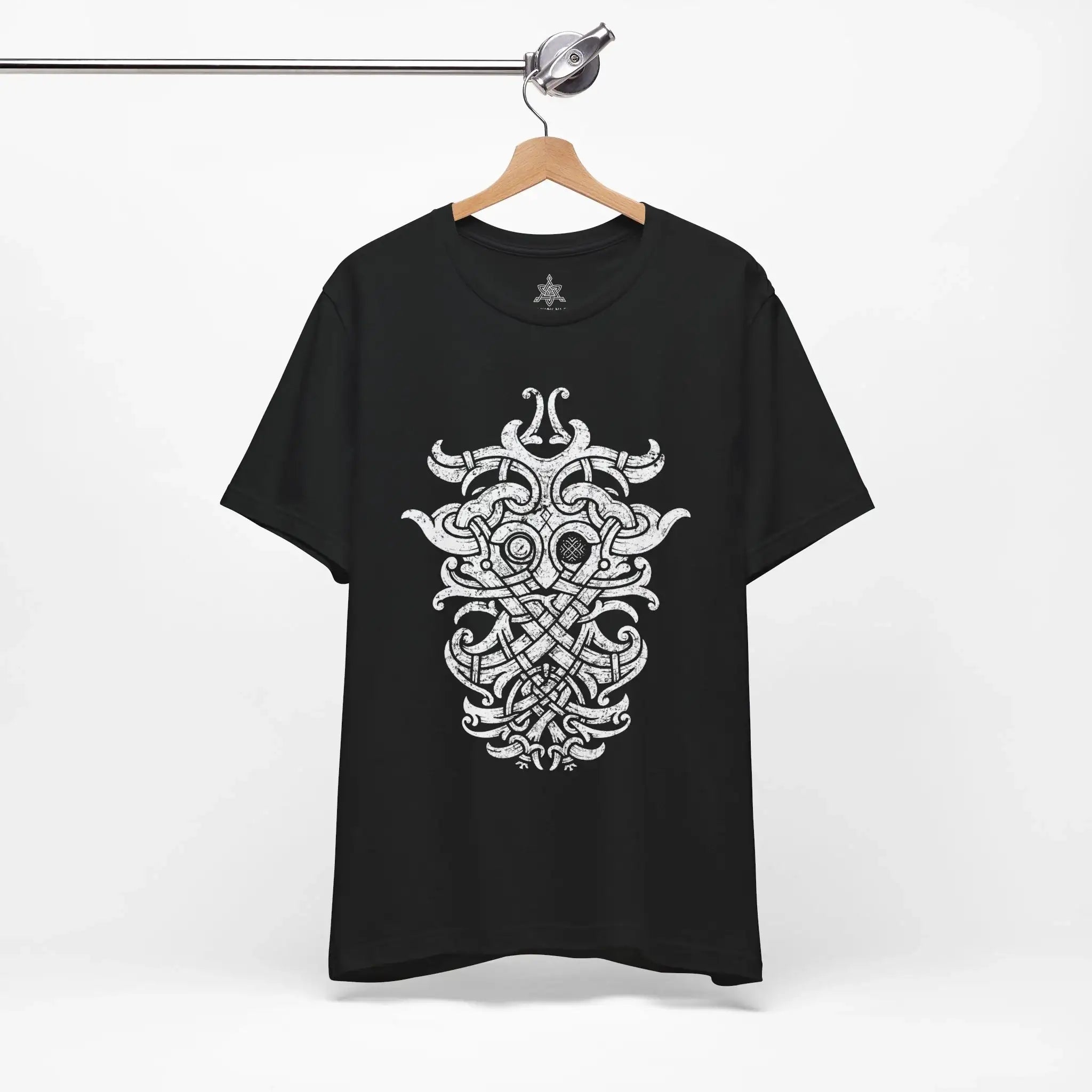 A black short-sleeve t-shirt hanging on a wooden hanger from a metal rack, featuring a large white Norse knotwork design printed on the front.