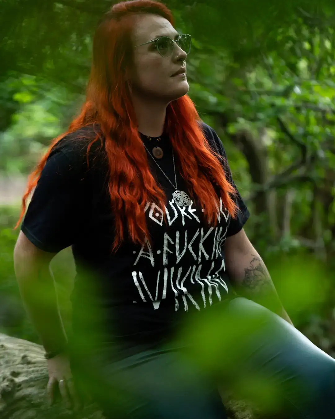 Woman with red hair wearing Norse-inspired Viking t-shirt in forest, bold rune-style graphic