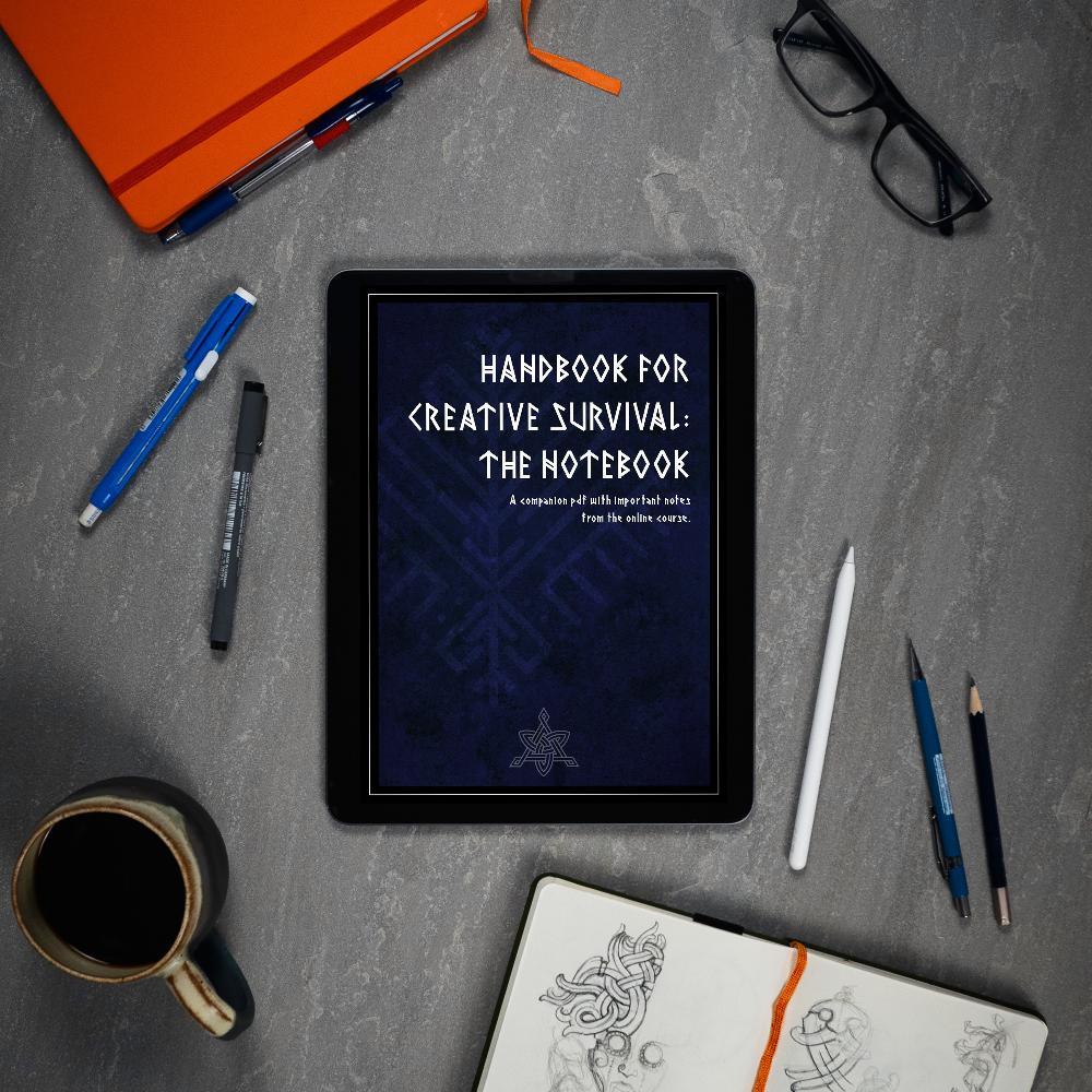 Handbook for Creative Survival: The Notebook displayed on tablet with Norse sketchbook, pens, and coffee