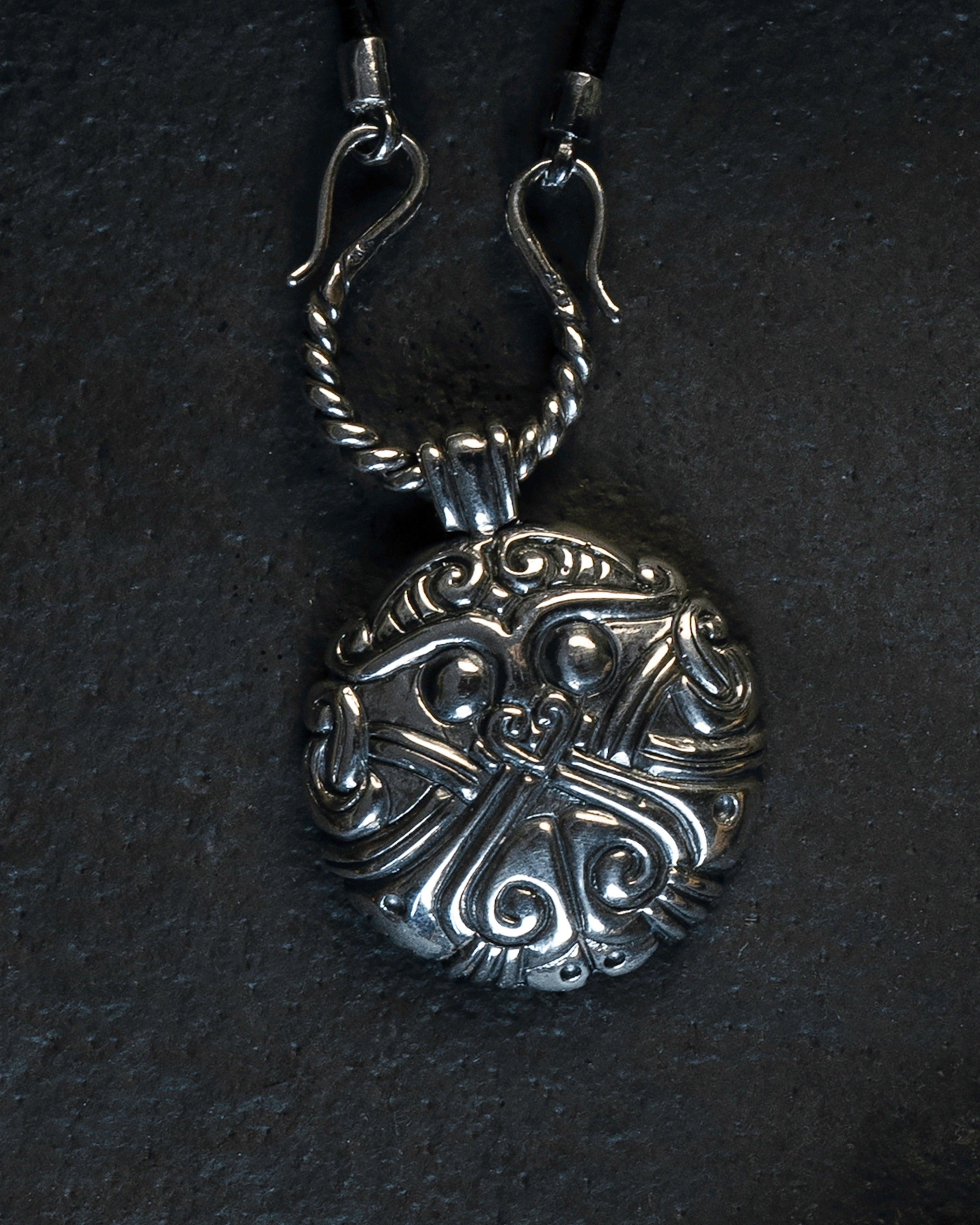 Intricate Norse-inspired silver pendant with Viking knotwork design on dark background