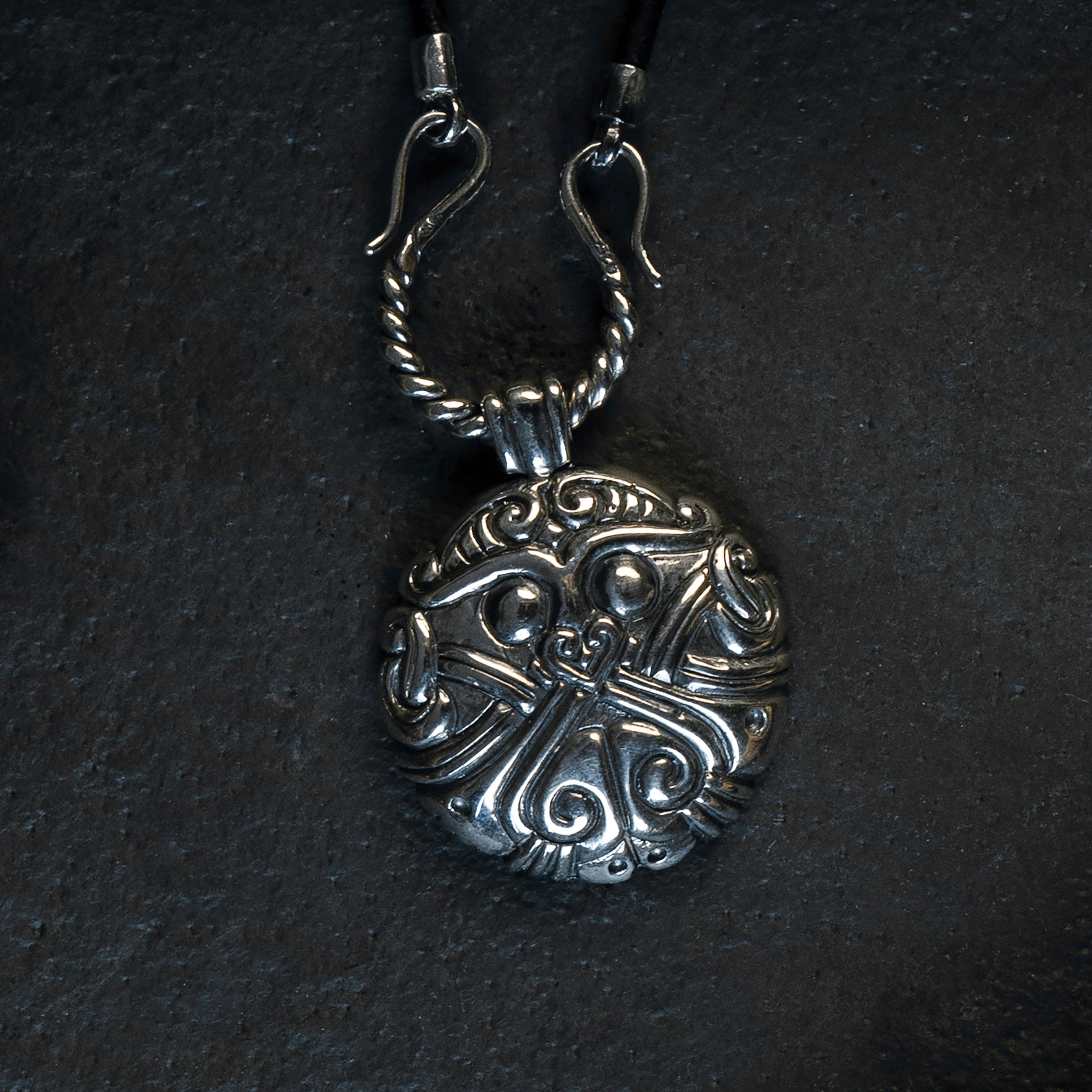 Intricate Norse-inspired silver pendant with Viking knotwork design on dark background