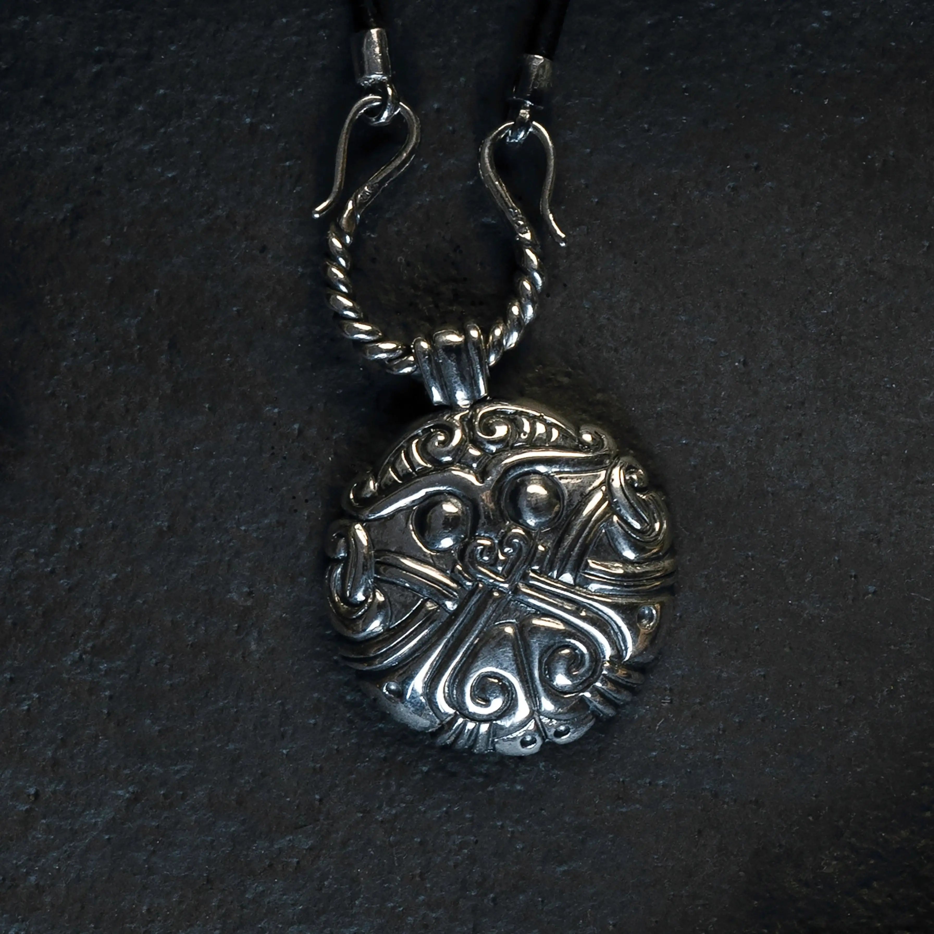Intricate Norse-inspired silver pendant with Viking knotwork design on dark background