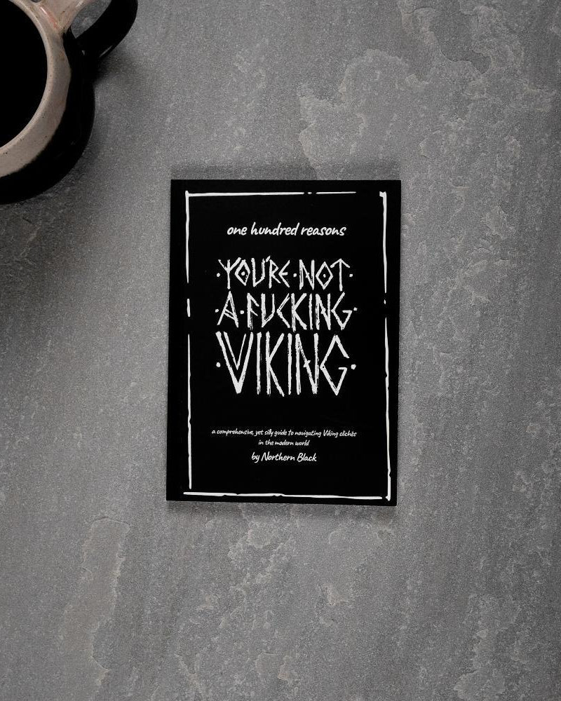 Viking-themed book titled 'You're Not a Fucking Viking' on gray surface with coffee mug