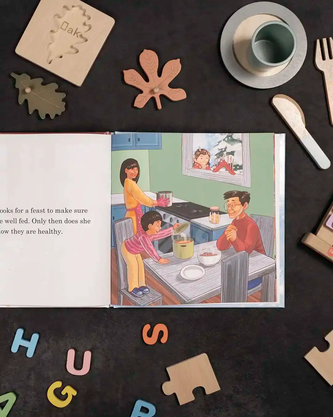 Children's book page showing family cooking together, surrounded by wooden leaf puzzles and alphabet letters