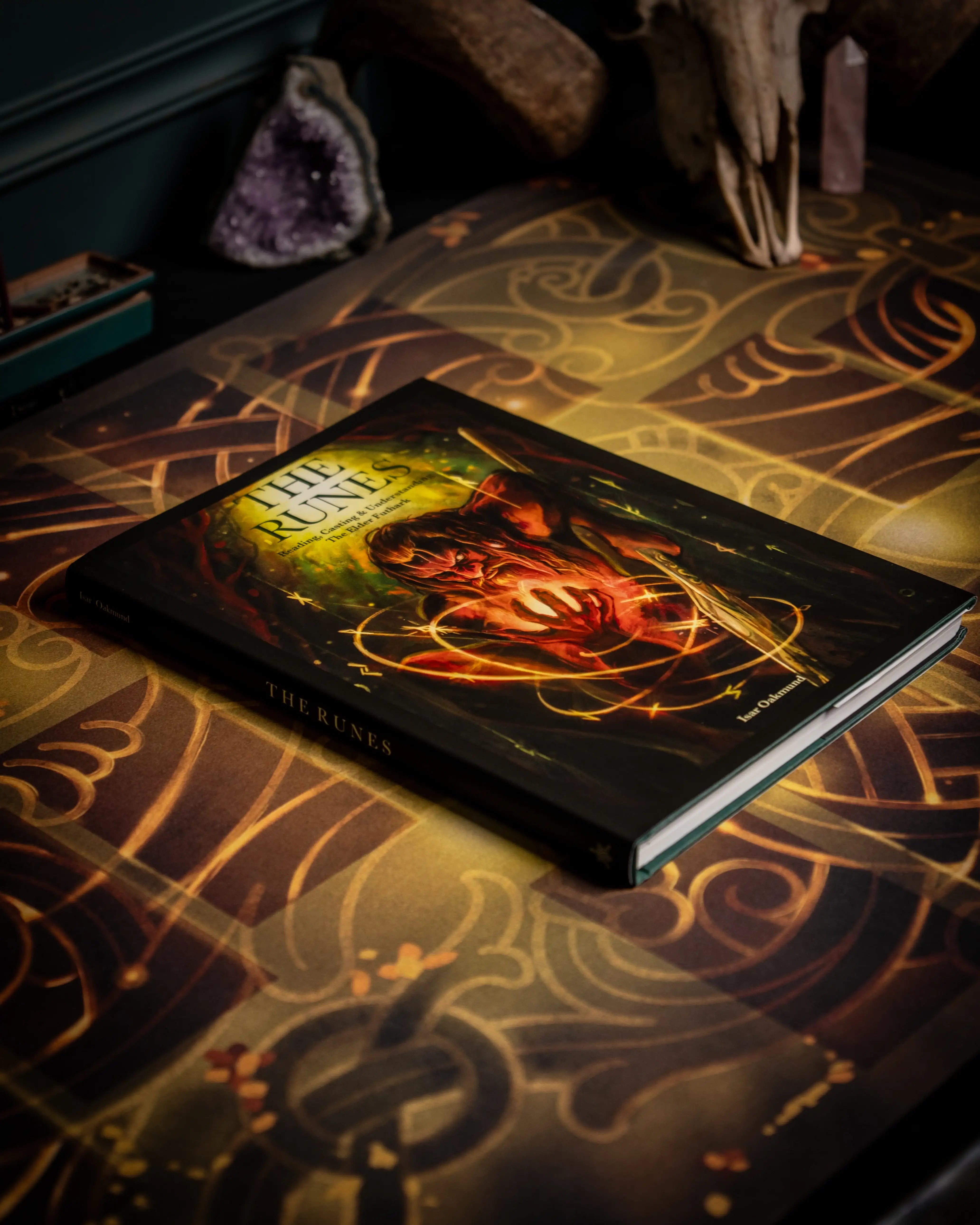 The Runes book by Isar Oakmund on Norse-inspired altar with amethyst and skull, featuring Elder Futhark designs