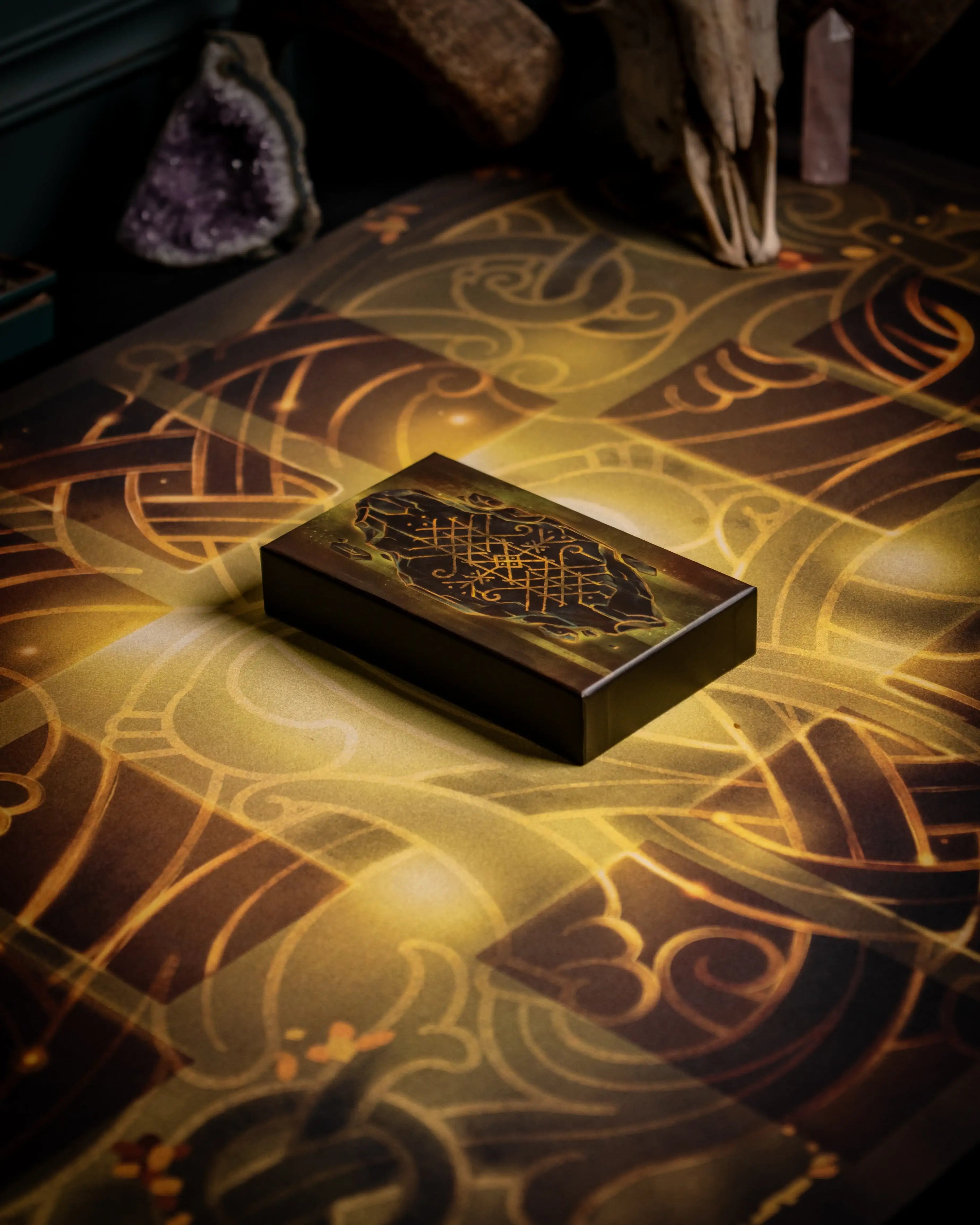 Norse-inspired box with golden runes on ornate patterned surface, surrounded by crystals and artifacts