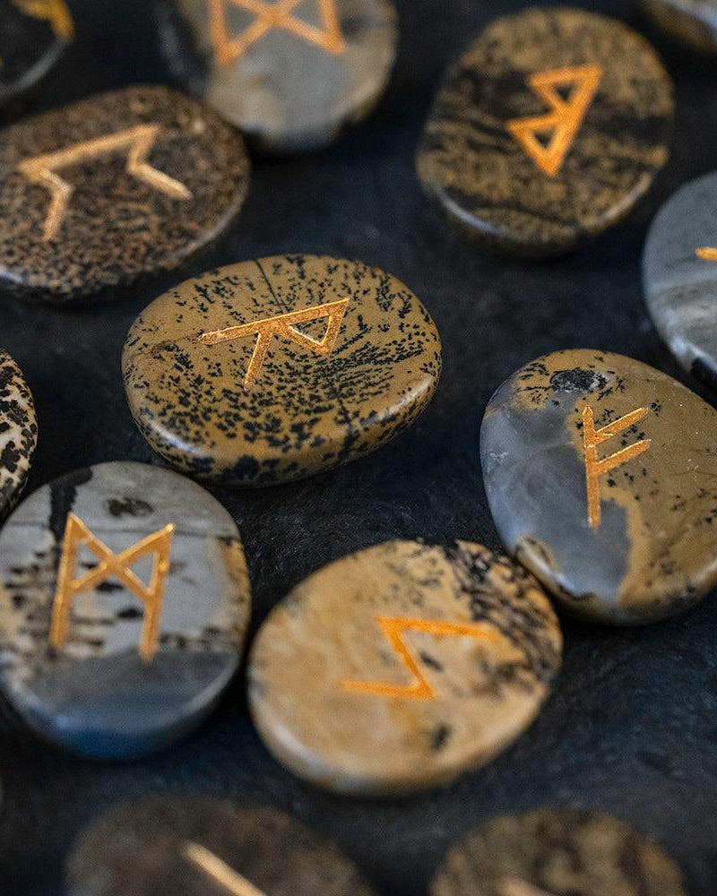 Hand-carved Norse runes on natural stone, gold-etched for Viking-inspired decor and spiritual practice.