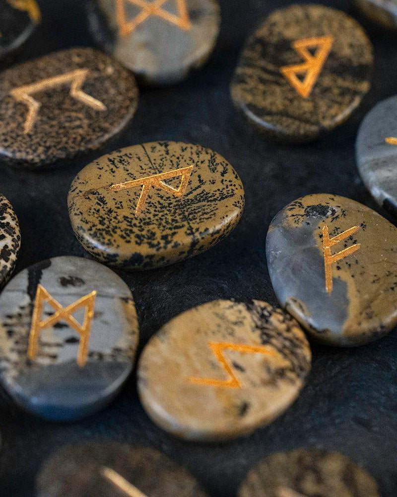 Hand-carved Norse runes on natural stone, gold-etched for Viking-inspired decor and spiritual practice.