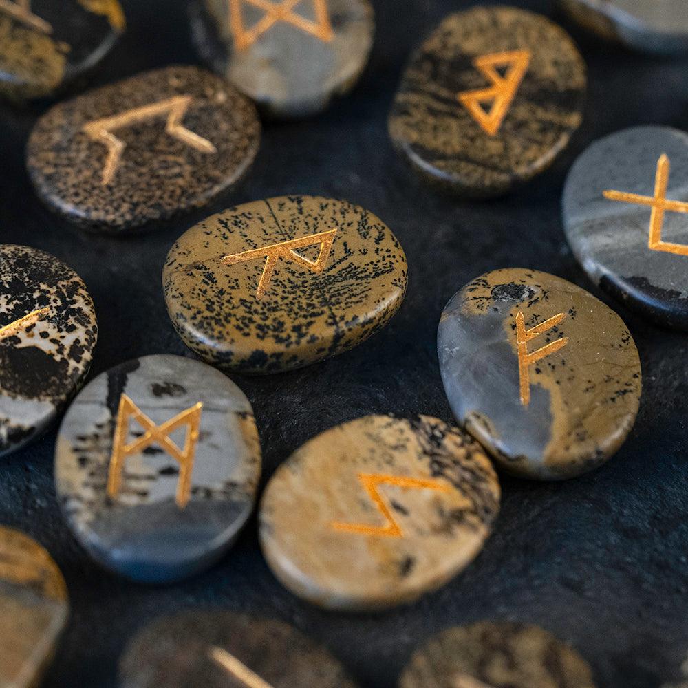 Hand-carved Norse runes on natural stone, gold-etched for Viking-inspired decor and spiritual practice.