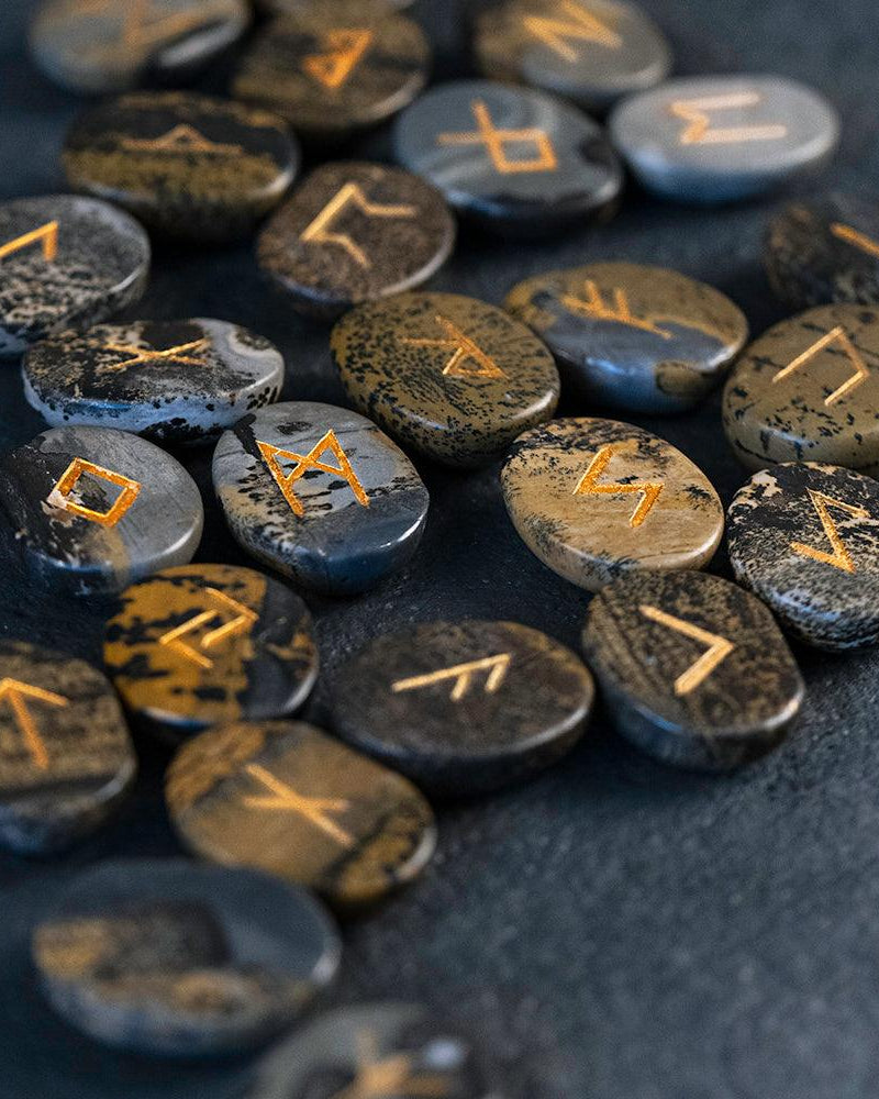 Norse rune stones with golden inscriptions on dark textured surface, authentic Viking symbols