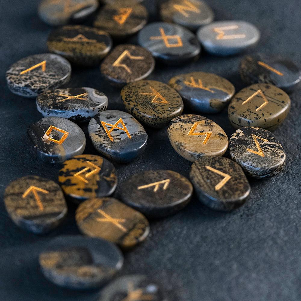 Norse rune stones with golden inscriptions on dark textured surface, authentic Viking symbols