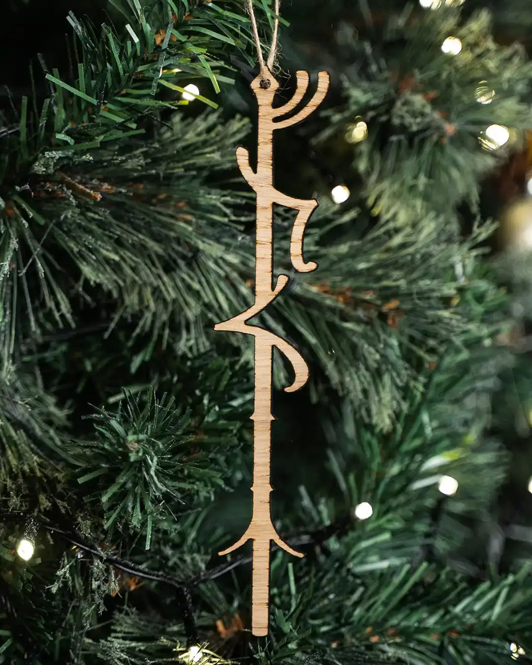Wooden Norse rune ornament hanging on Christmas tree with twinkling lights