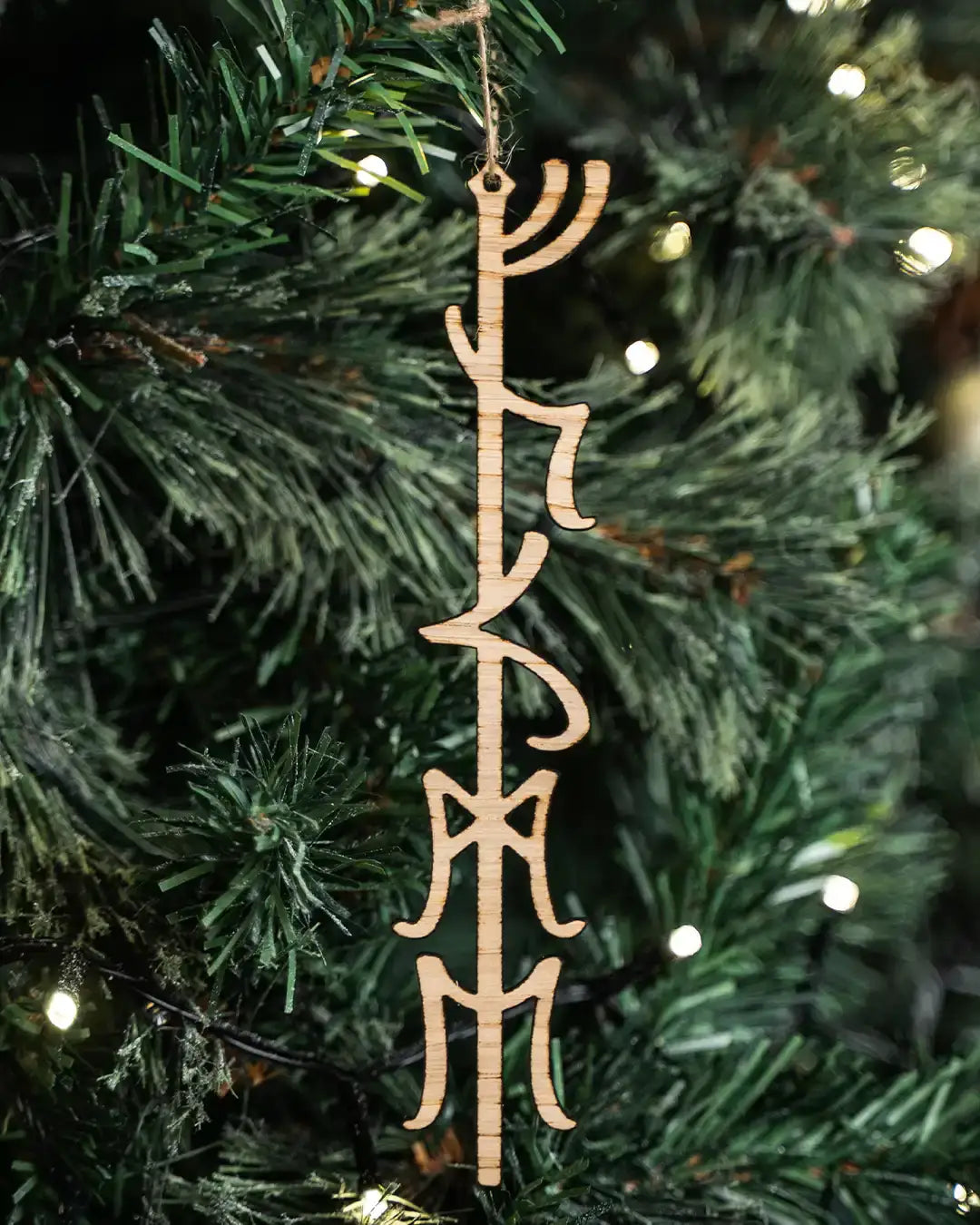 Wooden Norse rune ornament hanging on a lit Christmas tree, featuring authentic Viking-inspired design.