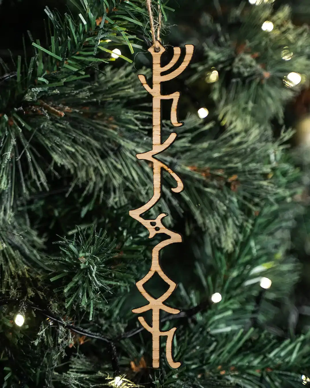 Wooden Norse rune ornament hanging on a lit Christmas tree, featuring authentic Viking-inspired design.