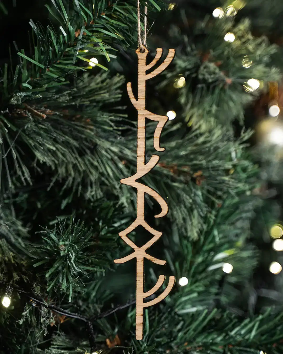 Wooden Norse rune ornament hanging on a Christmas tree with warm lights