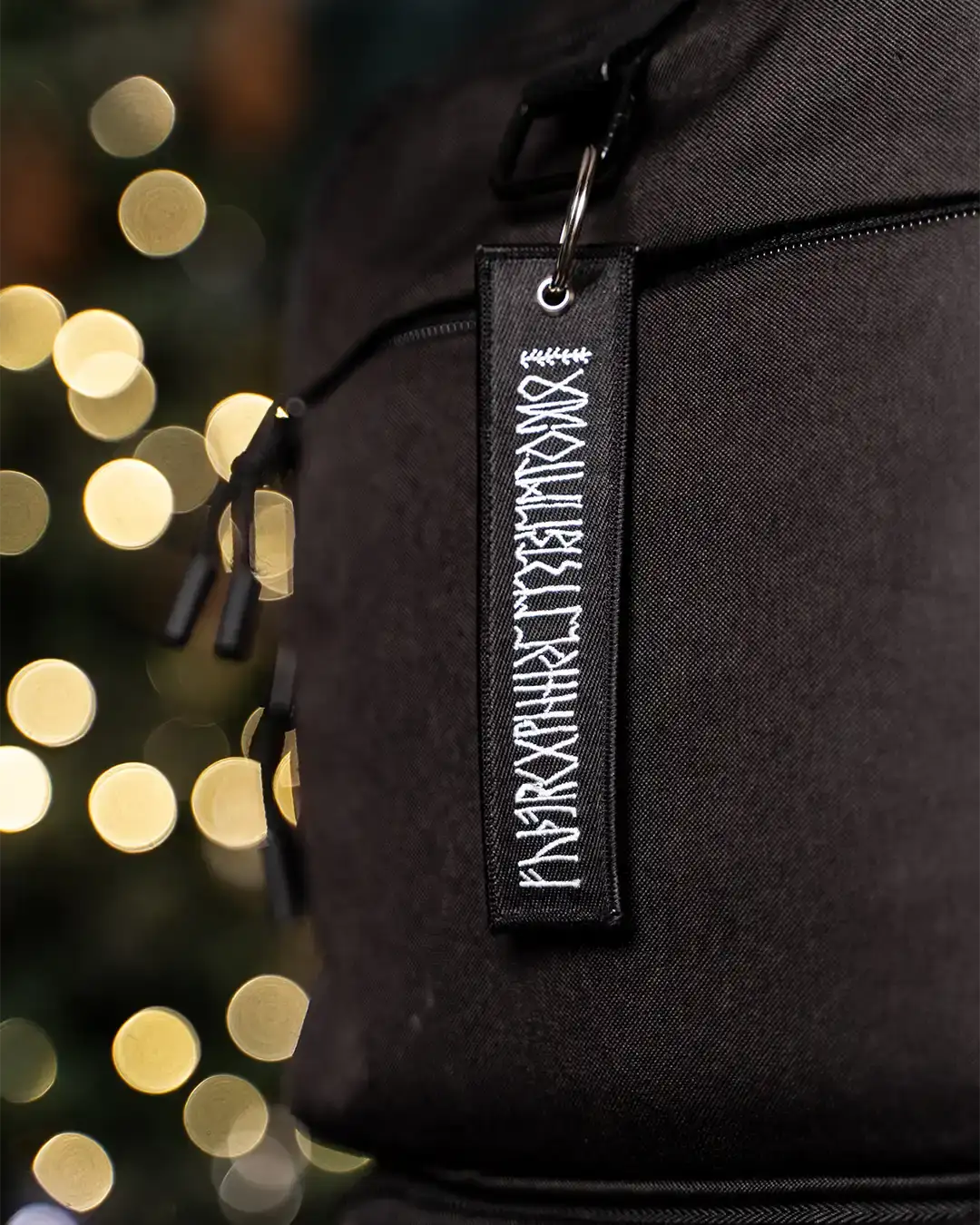 Black backpack with Norse rune embroidery, festive bokeh lights background
