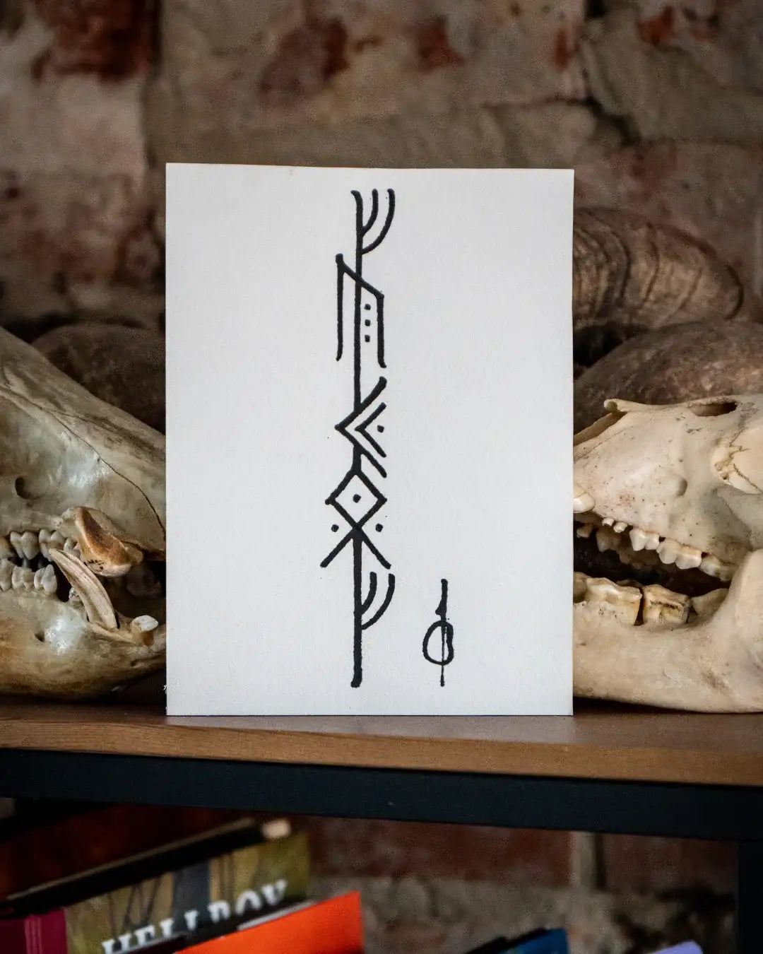 Norse rune art print with Viking-inspired symbols, displayed beside animal skulls on a shelf