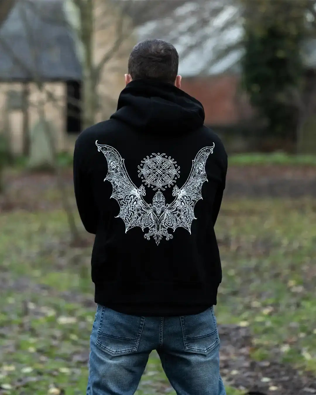 Black hoodie with intricate Norse-inspired bat and rune design, worn outdoors