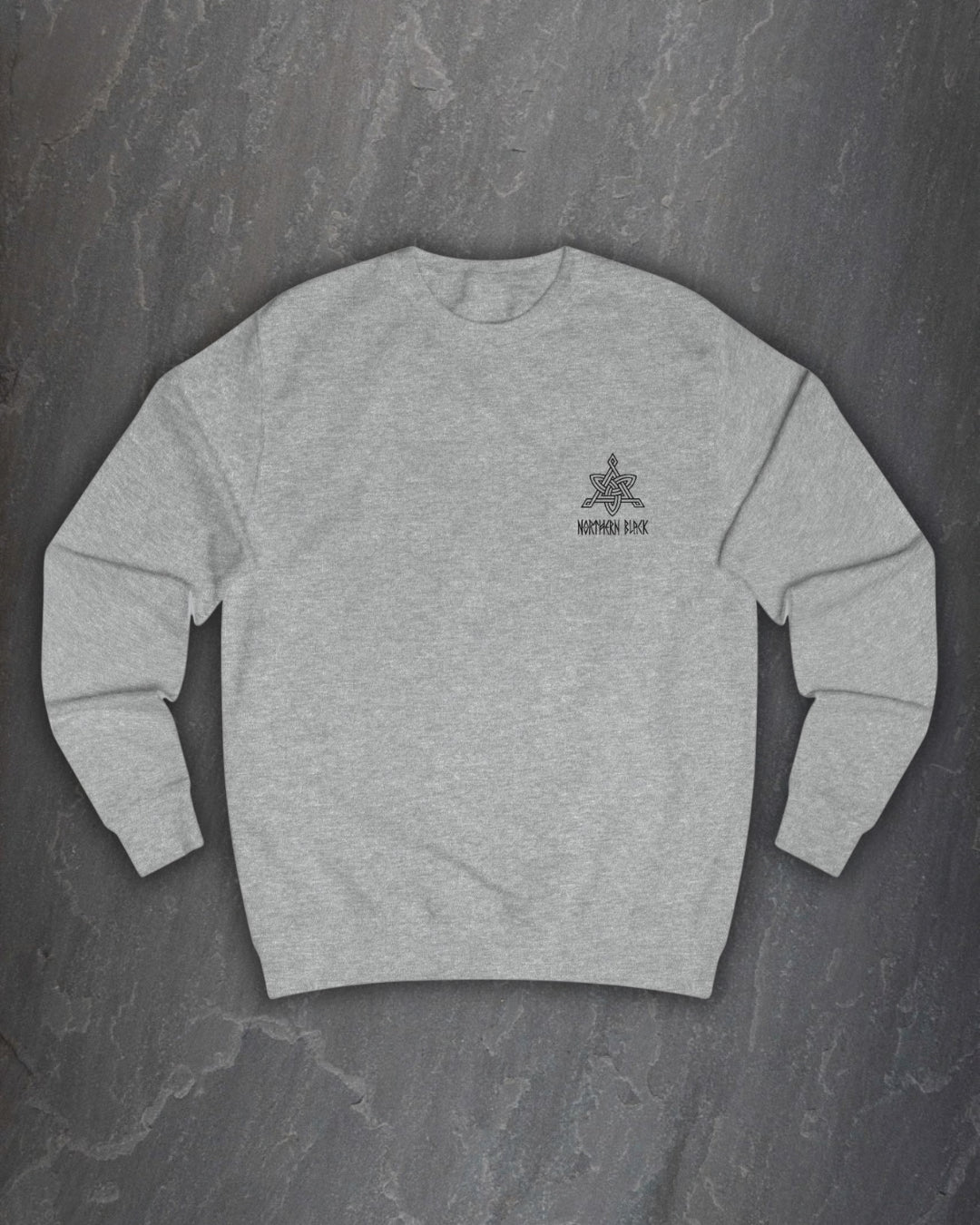 Front of a heather grey Lifthrasir sweatshirt with a small Northern Black logo on the chest on a dark slate background
