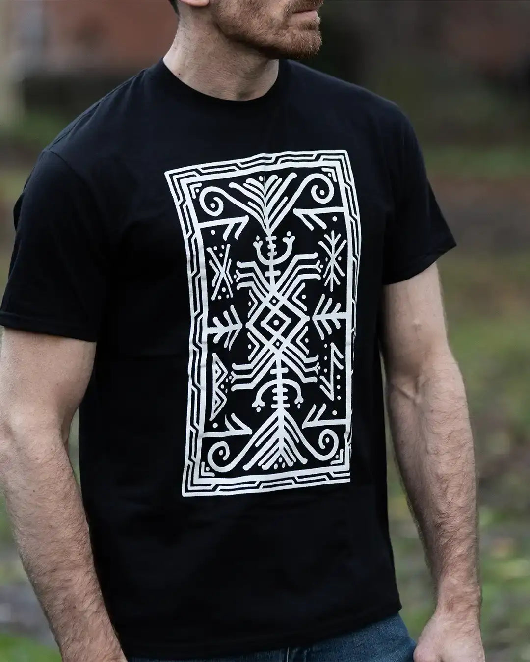 Man wearing black t-shirt with white Norse-inspired geometric tattoo design, Viking art style