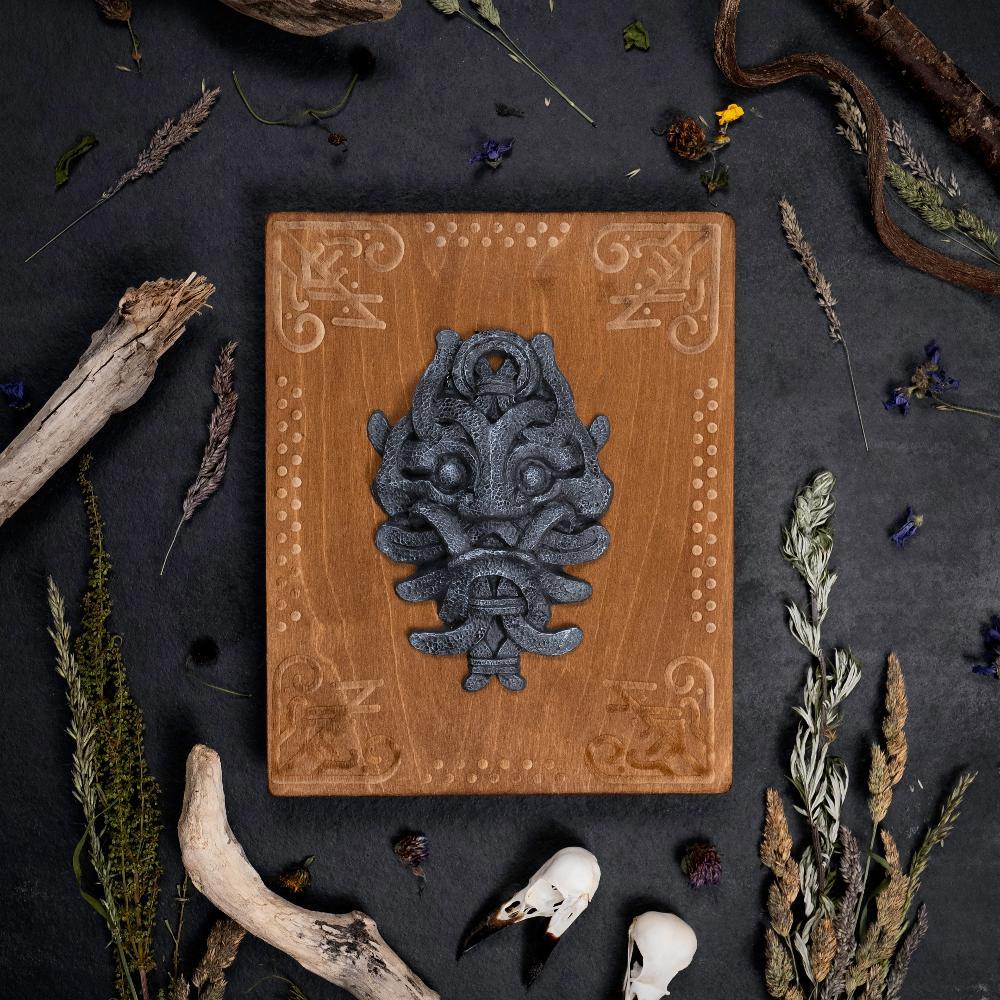 Viking-inspired wooden plaque with Norse beast carving, surrounded by dried herbs and bones