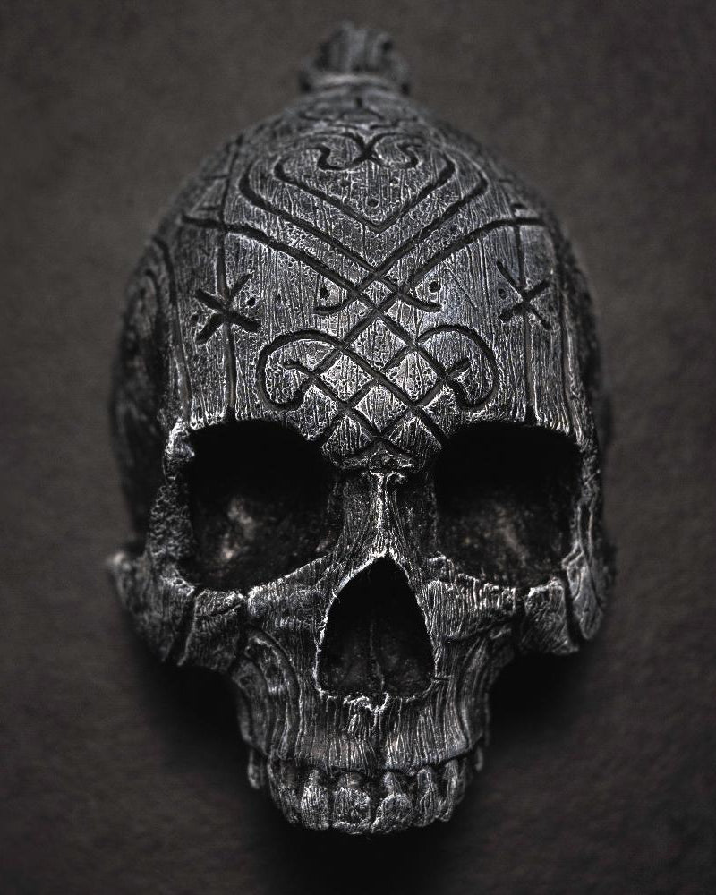 Depicting one of three skulls that are in a collection. They are resin human shaped skulls with runes on them, each representing one of the following: Love, Lust, Loss.