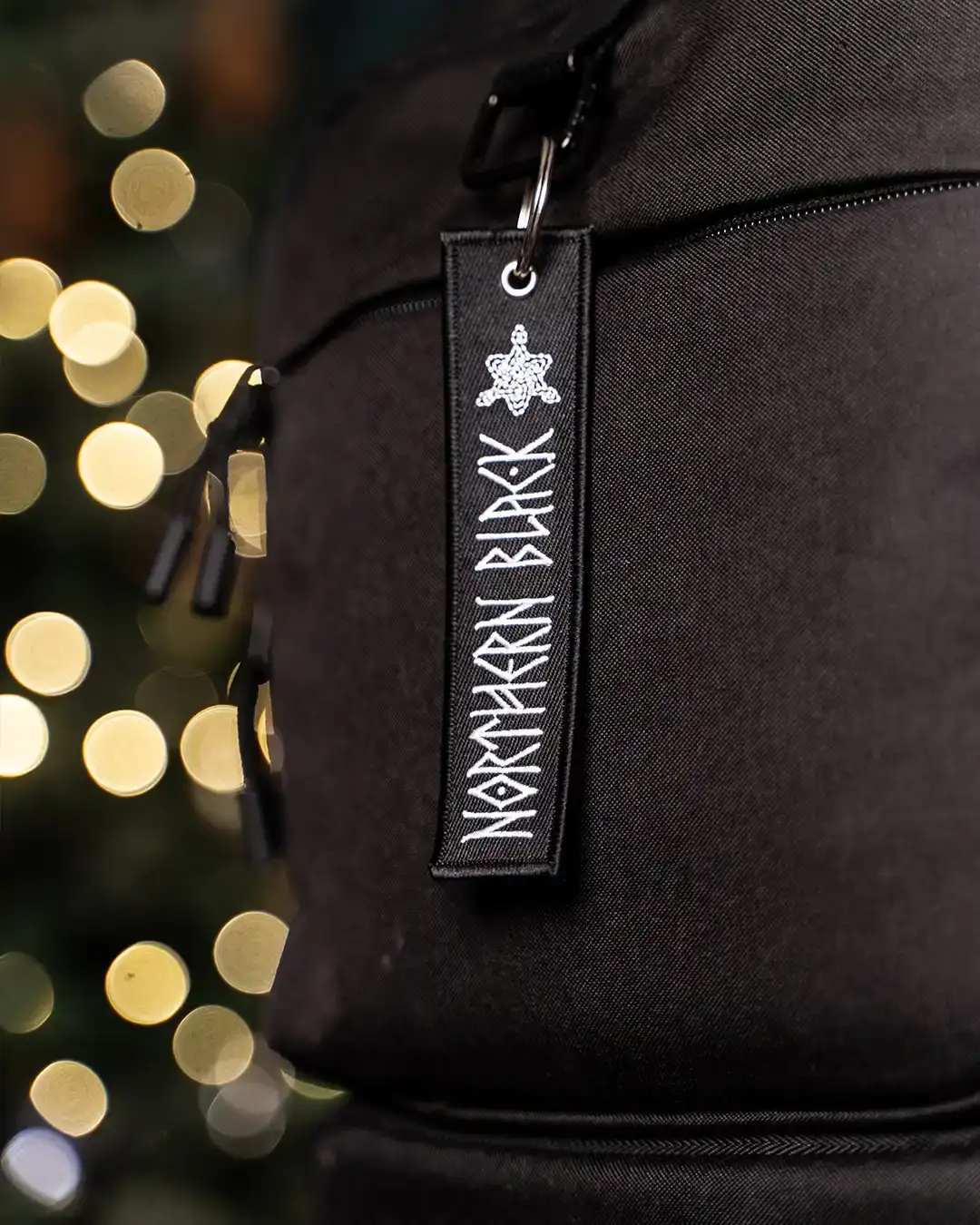 Black backpack with Northern Black rune tag, festive bokeh lights background