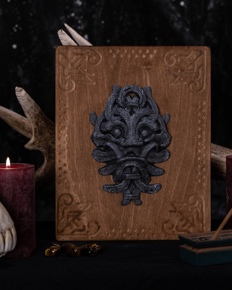 Stone looking engraving sculpture of the mask of Odin, placed on an wooden plate engraved with runes