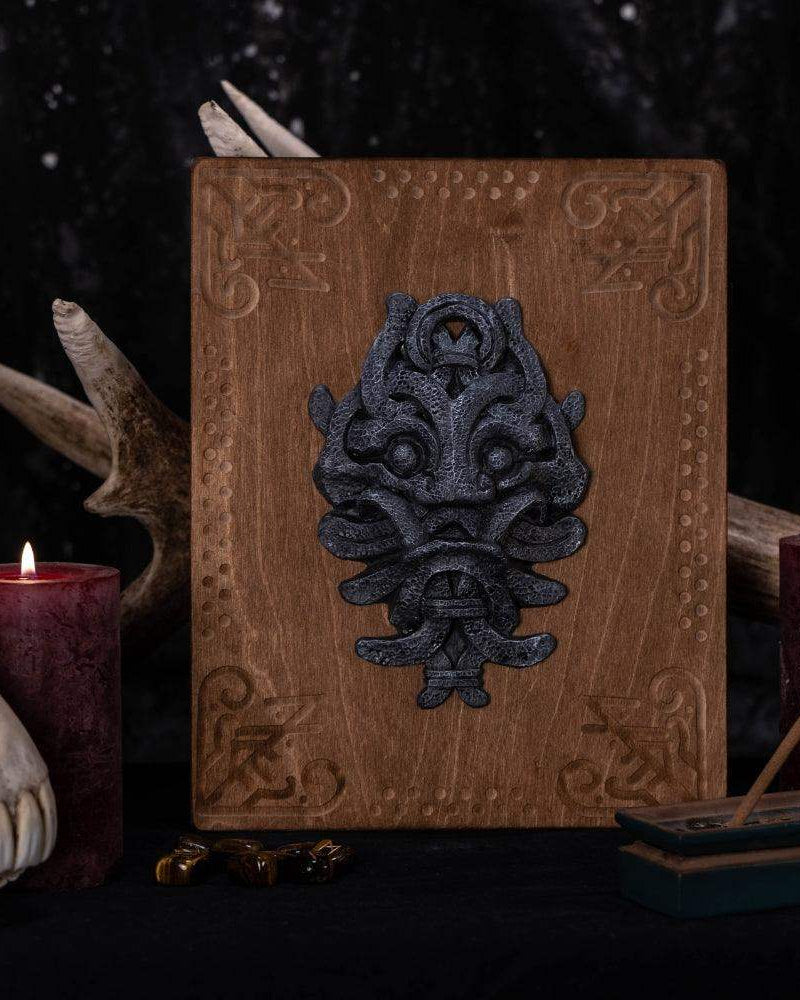 Norse-inspired wooden plaque with Viking mask design, surrounded by candles and antlers