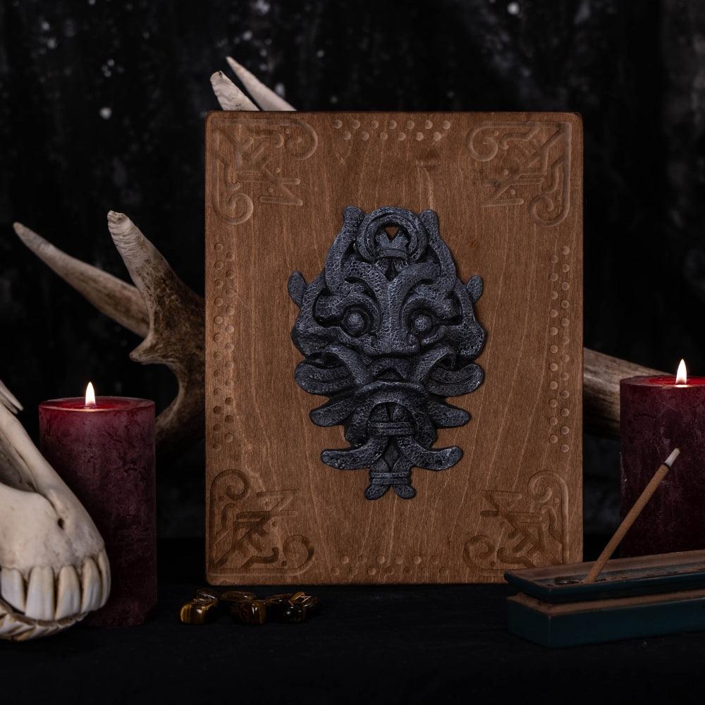 Norse-inspired wooden plaque with Viking mask design, surrounded by candles and antlers