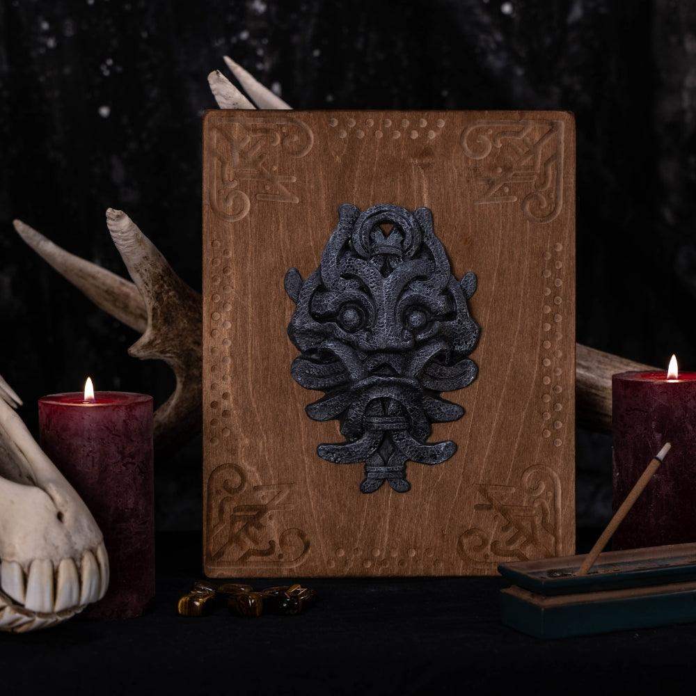 Norse-inspired wooden plaque with Viking mask design, surrounded by candles and antlers