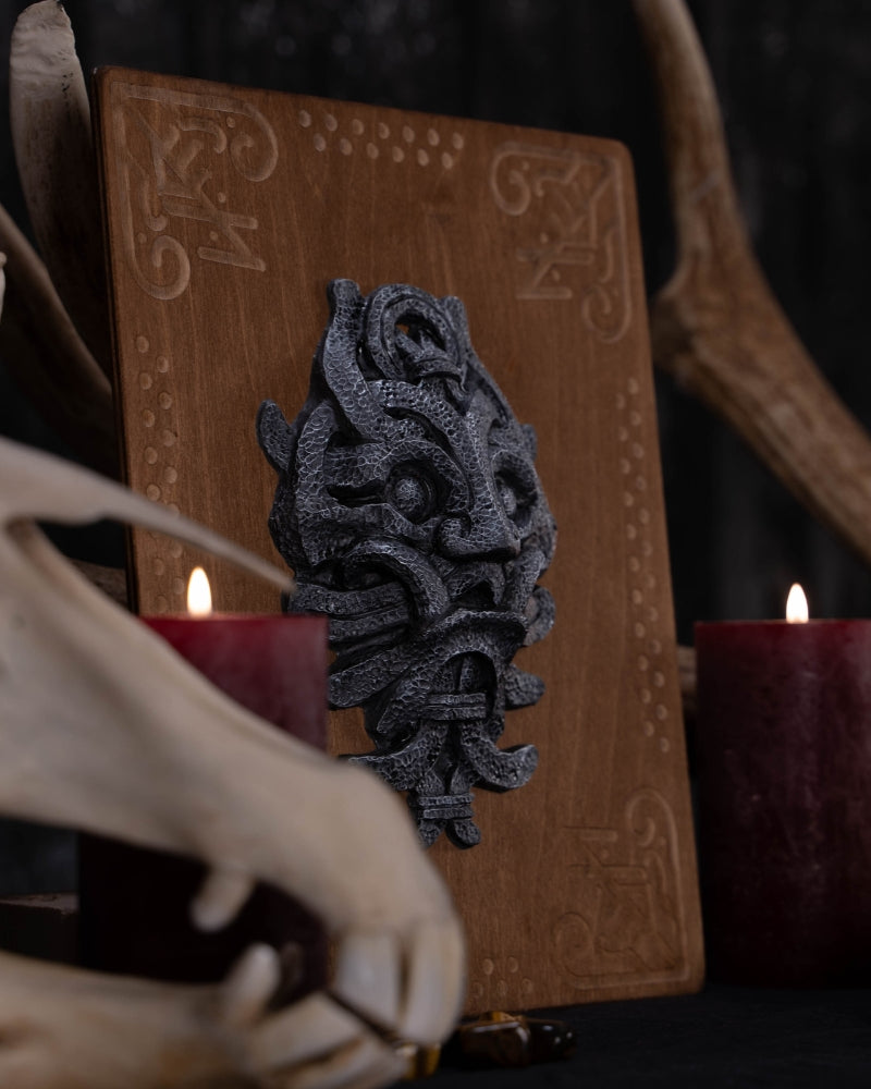 Stone looking engraving sculpture of the mask of Odin, placed on an wooden plate engraved with runes