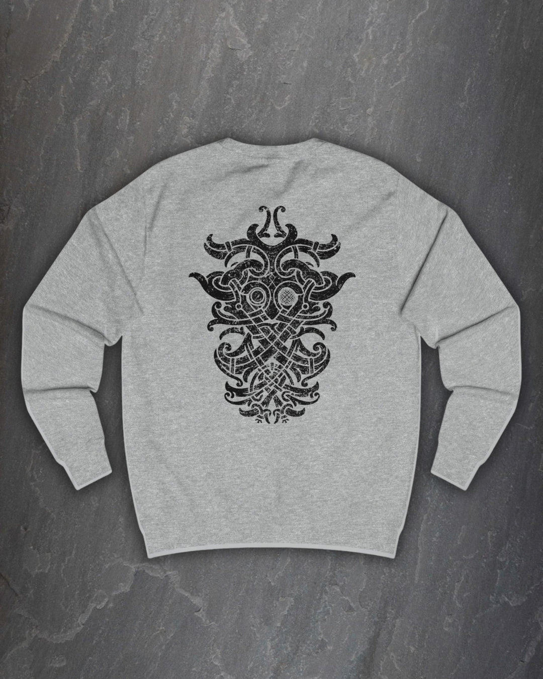 Back of a heather grey Odin Godmask sweatshirt with a large black Norse knotwork Odin mask print on a dark slate background
