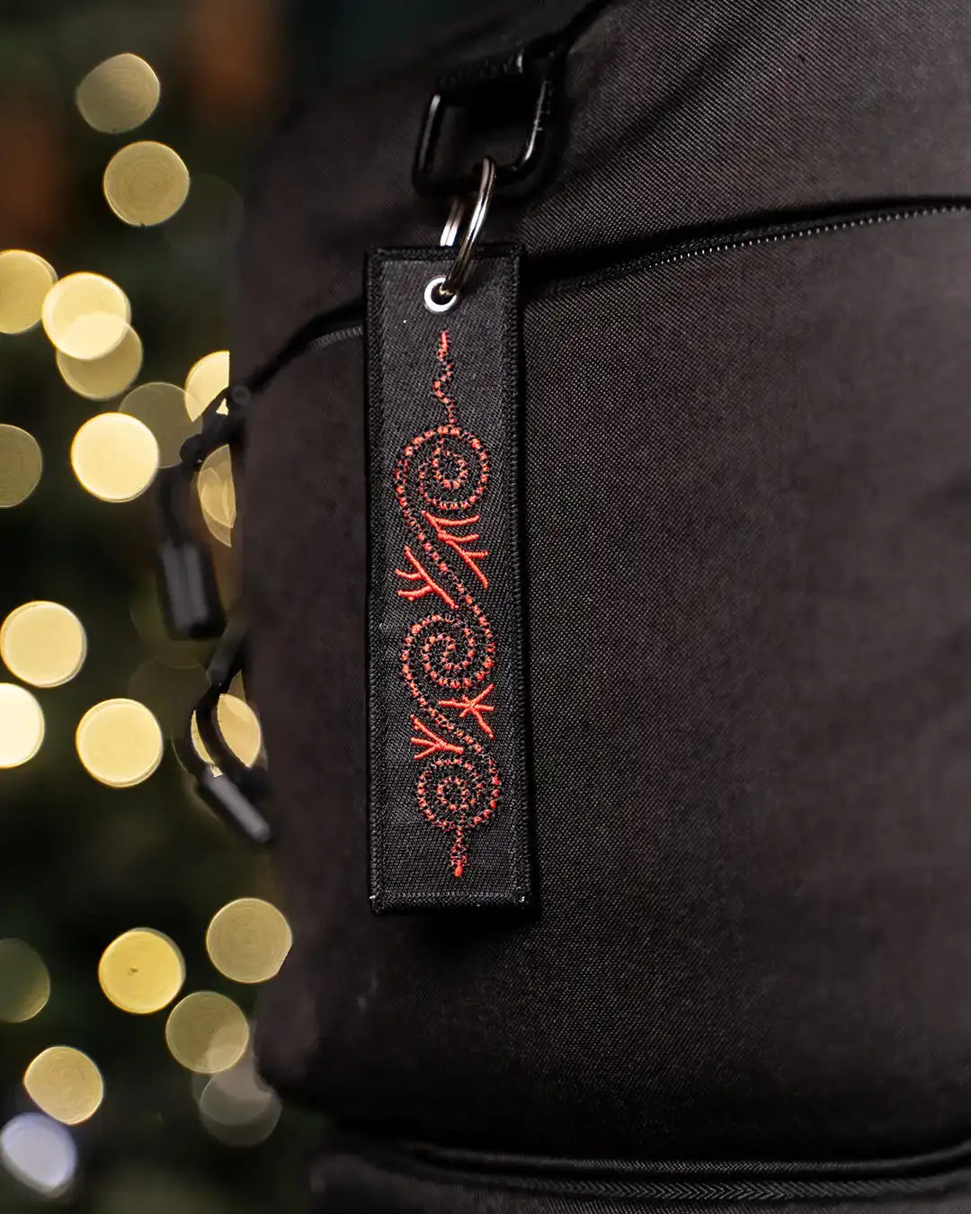 Black bag with red Norse rune embroidery tag, festive bokeh lights background