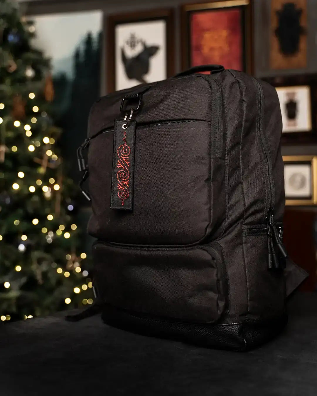 Black Norse-inspired backpack with red Viking knotwork tag, festive tree background