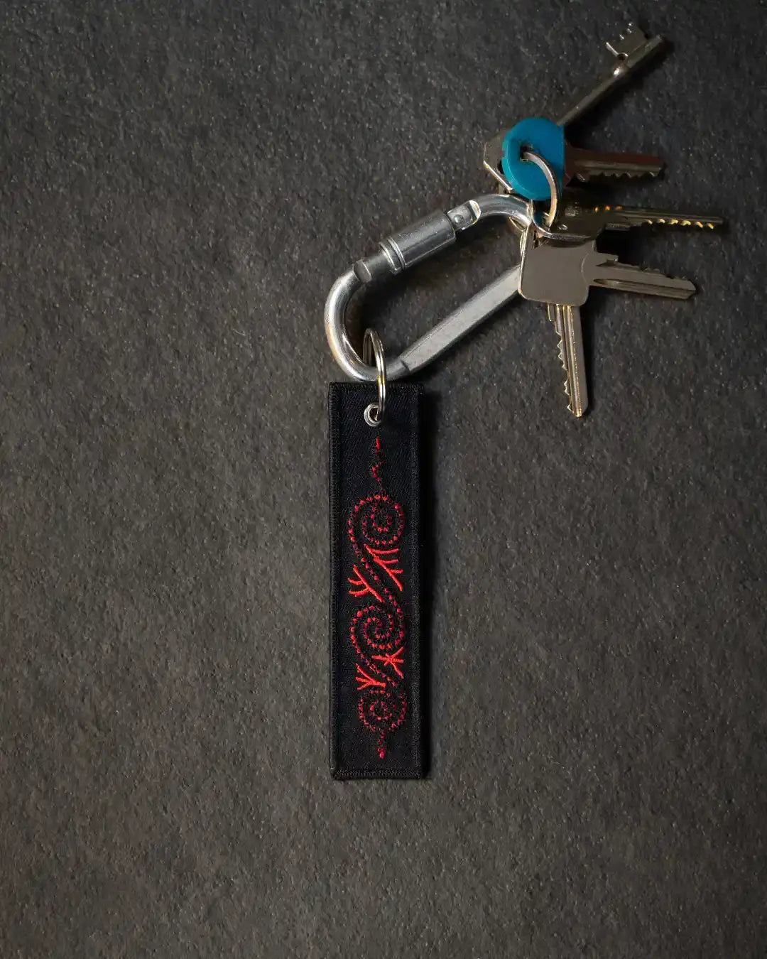 Black keychain with red Norse dragon embroidery, attached to metal carabiner and keys
