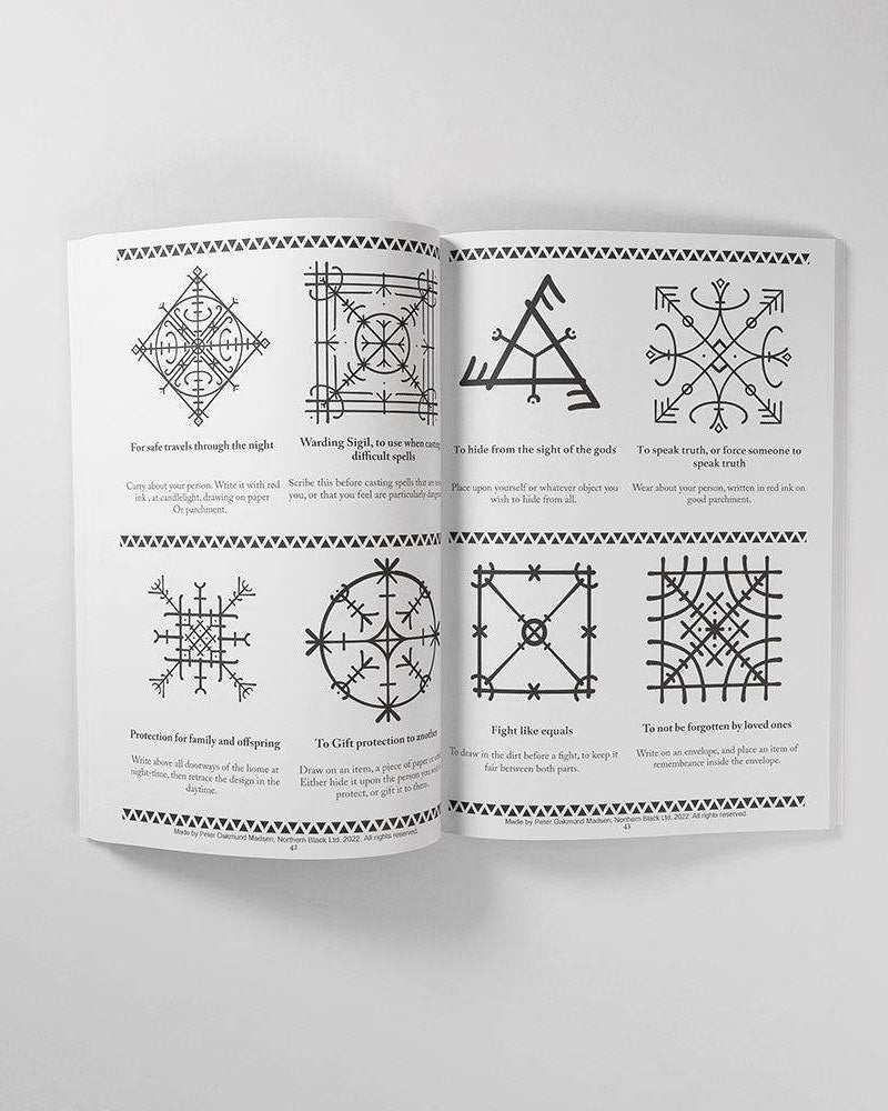 Norse rune symbols and Viking tattoo designs from authentic historical sources, shown in an open art book.