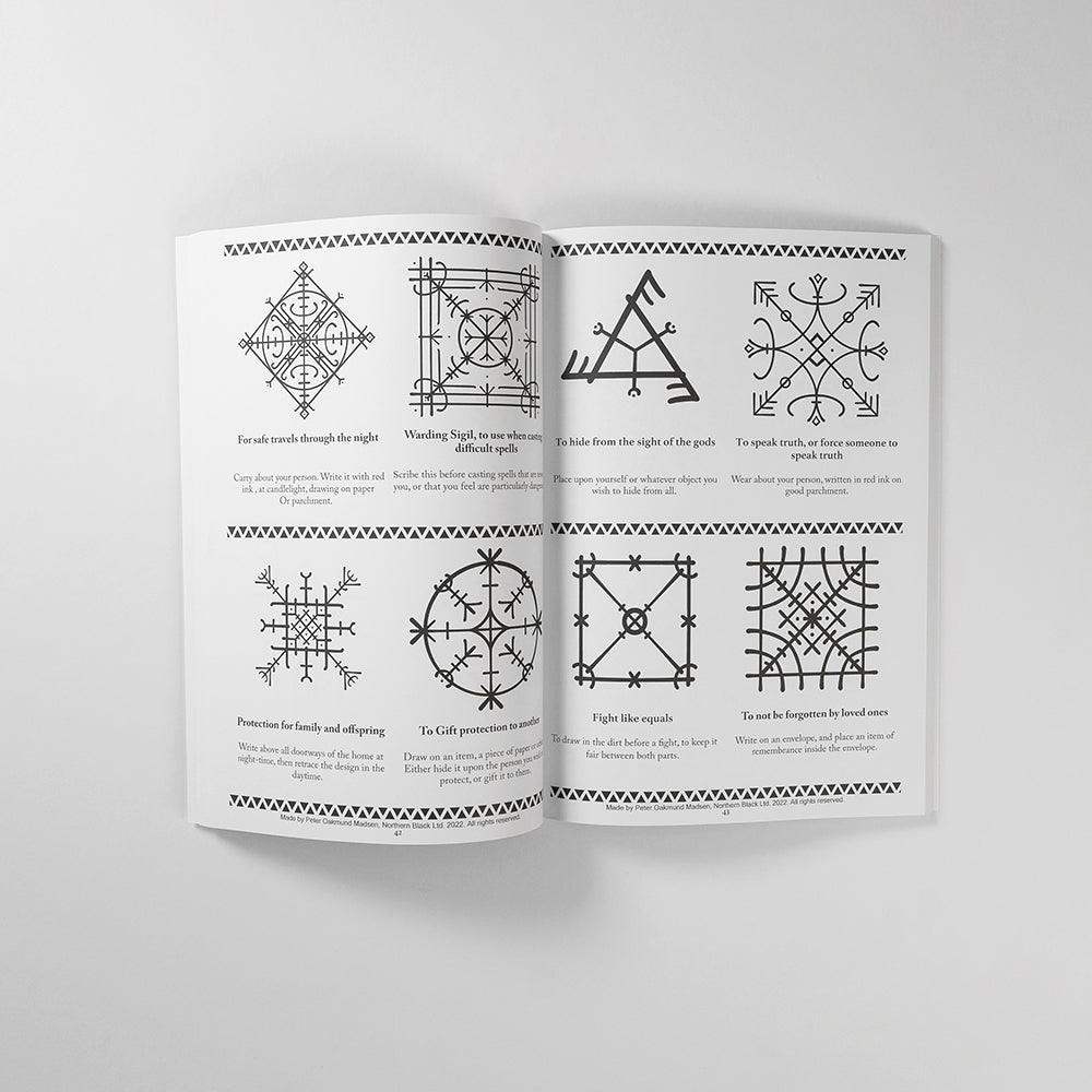 Norse rune symbols and Viking tattoo designs from authentic historical sources, shown in an open art book.