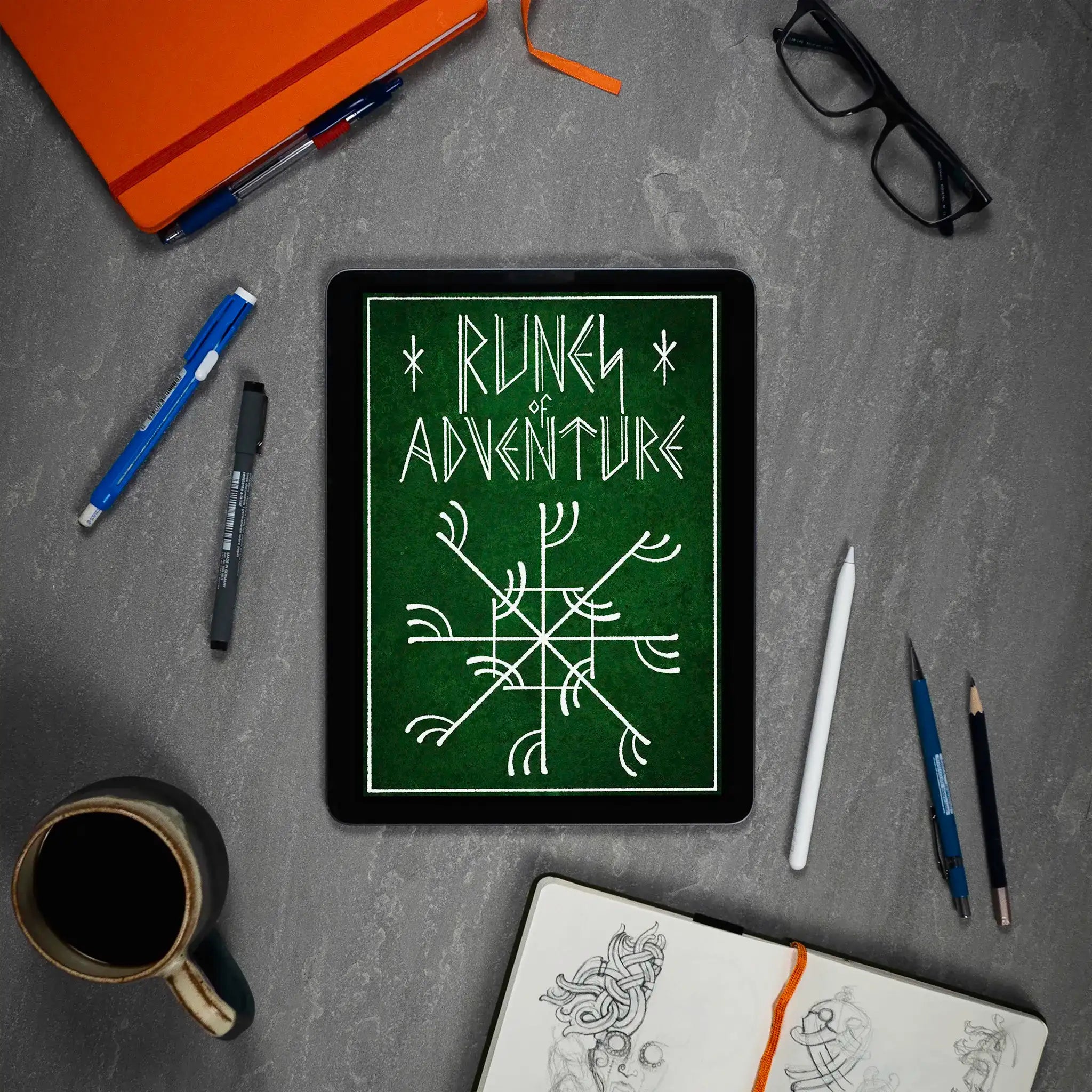 Tablet displaying 'Runes of Adventure' with Norse symbol, surrounded by sketchbook, pens, and coffee mug