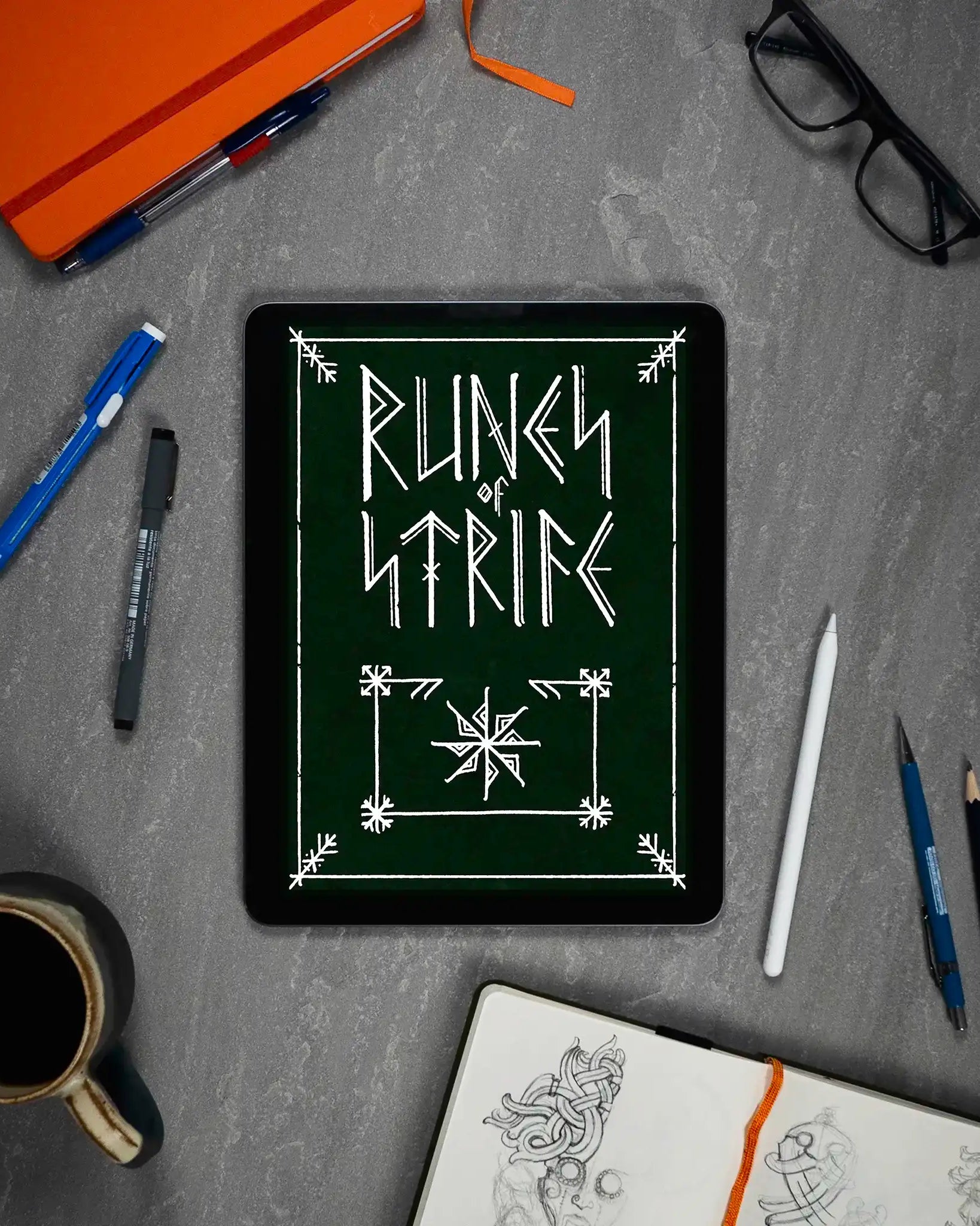 Runic design on tablet with Norse art sketches, pens, and coffee — Viking tattoo inspiration