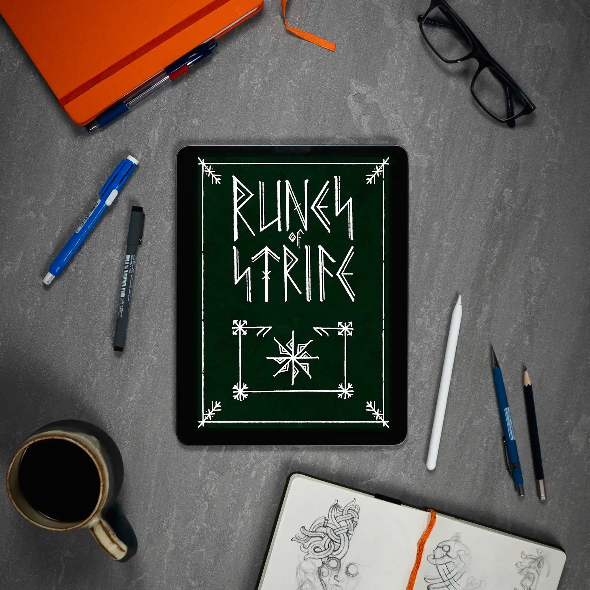 Runic design on tablet with Norse art sketches, pens, and coffee — Viking tattoo inspiration