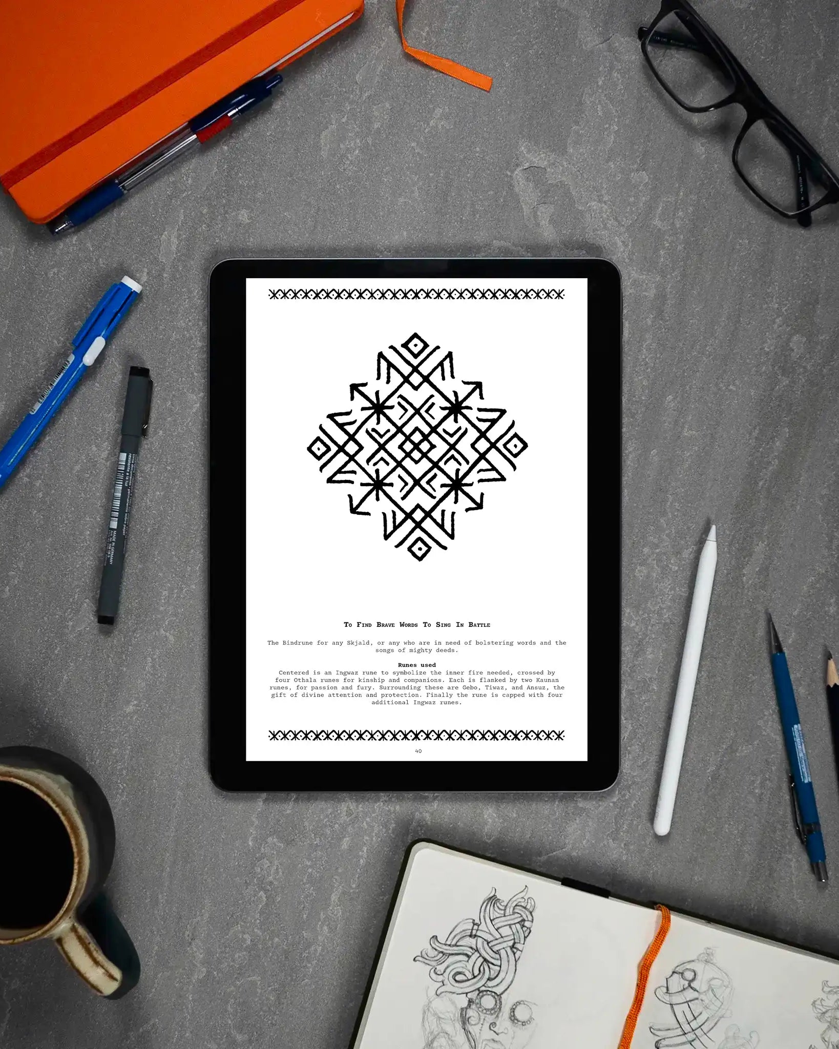 Norse rune design on tablet, Viking tattoo art guide with Ingwaz and Othala runes, surrounded by sketchbook and pens