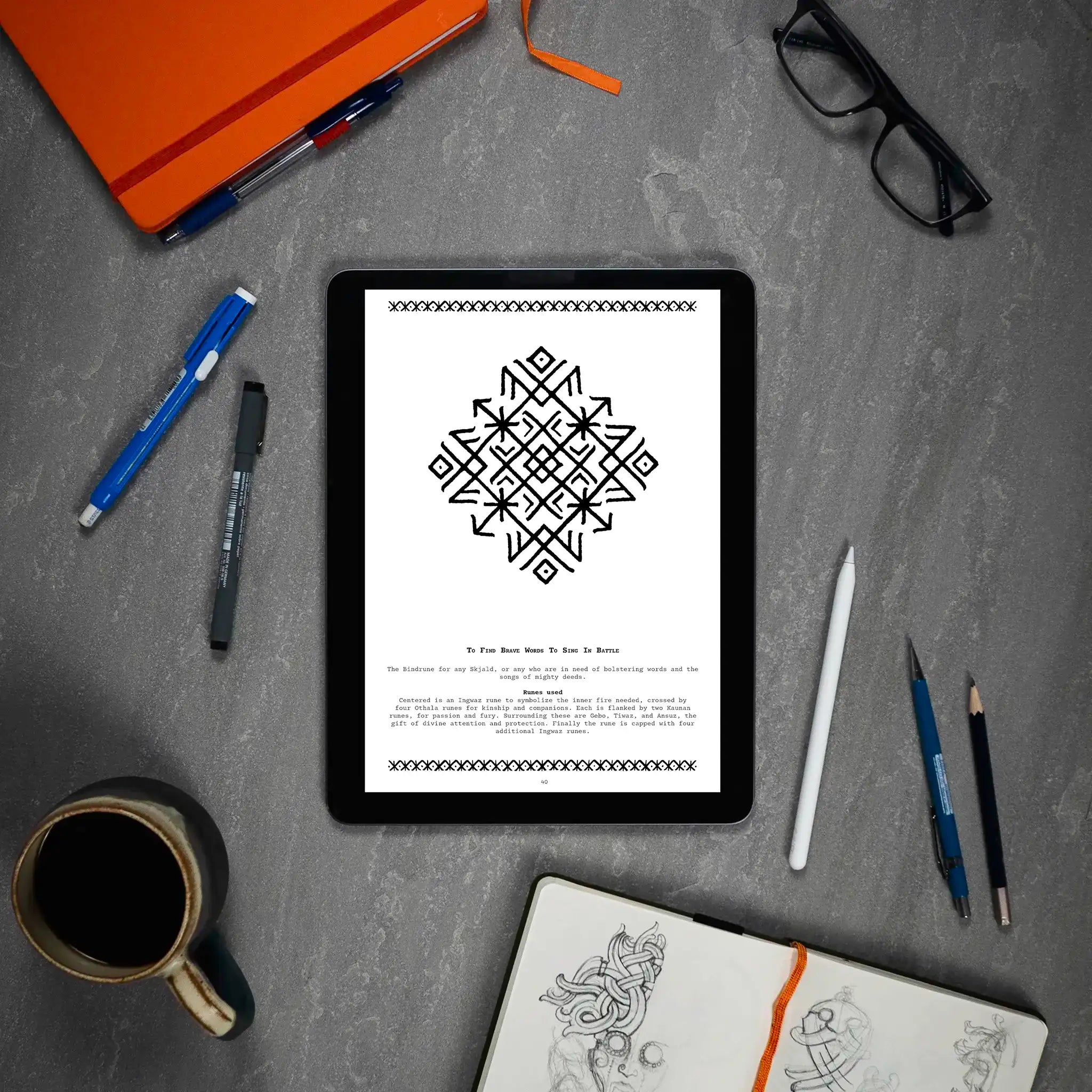 Norse rune design on tablet, Viking tattoo art guide with Ingwaz and Othala runes, surrounded by sketchbook and pens