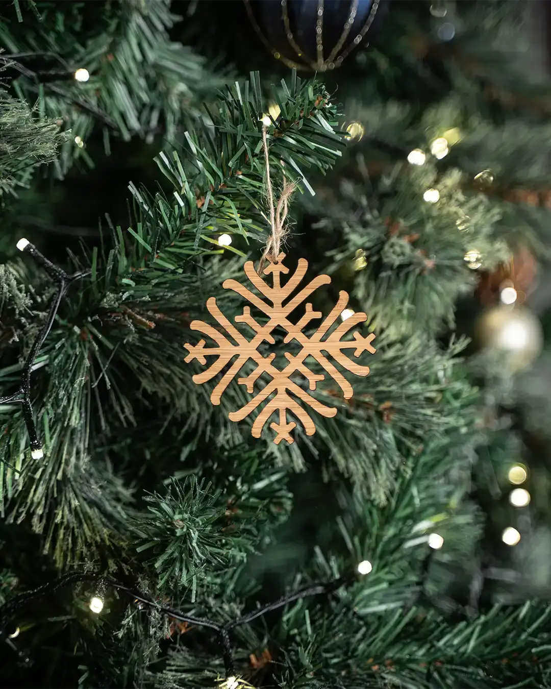 Wooden Norse snowflake ornament hanging on Christmas tree with warm lights