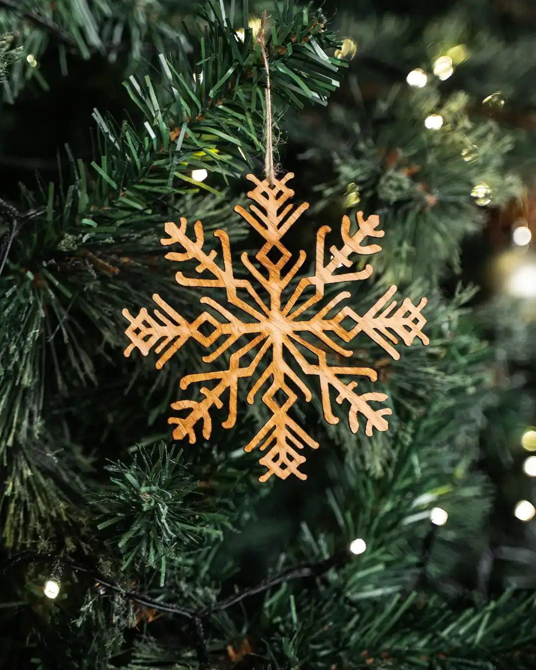 Wooden snowflake ornament with Norse rune design hanging on Christmas tree